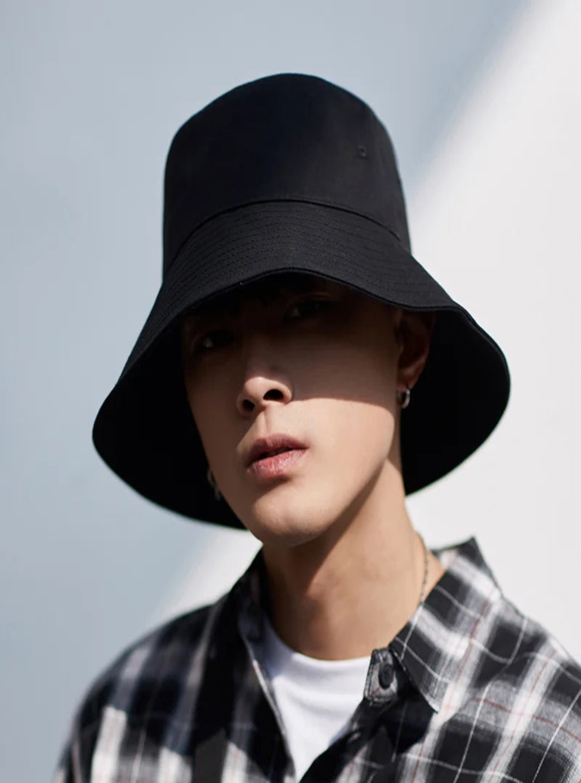 Person wearing a black bucket hat against a light background