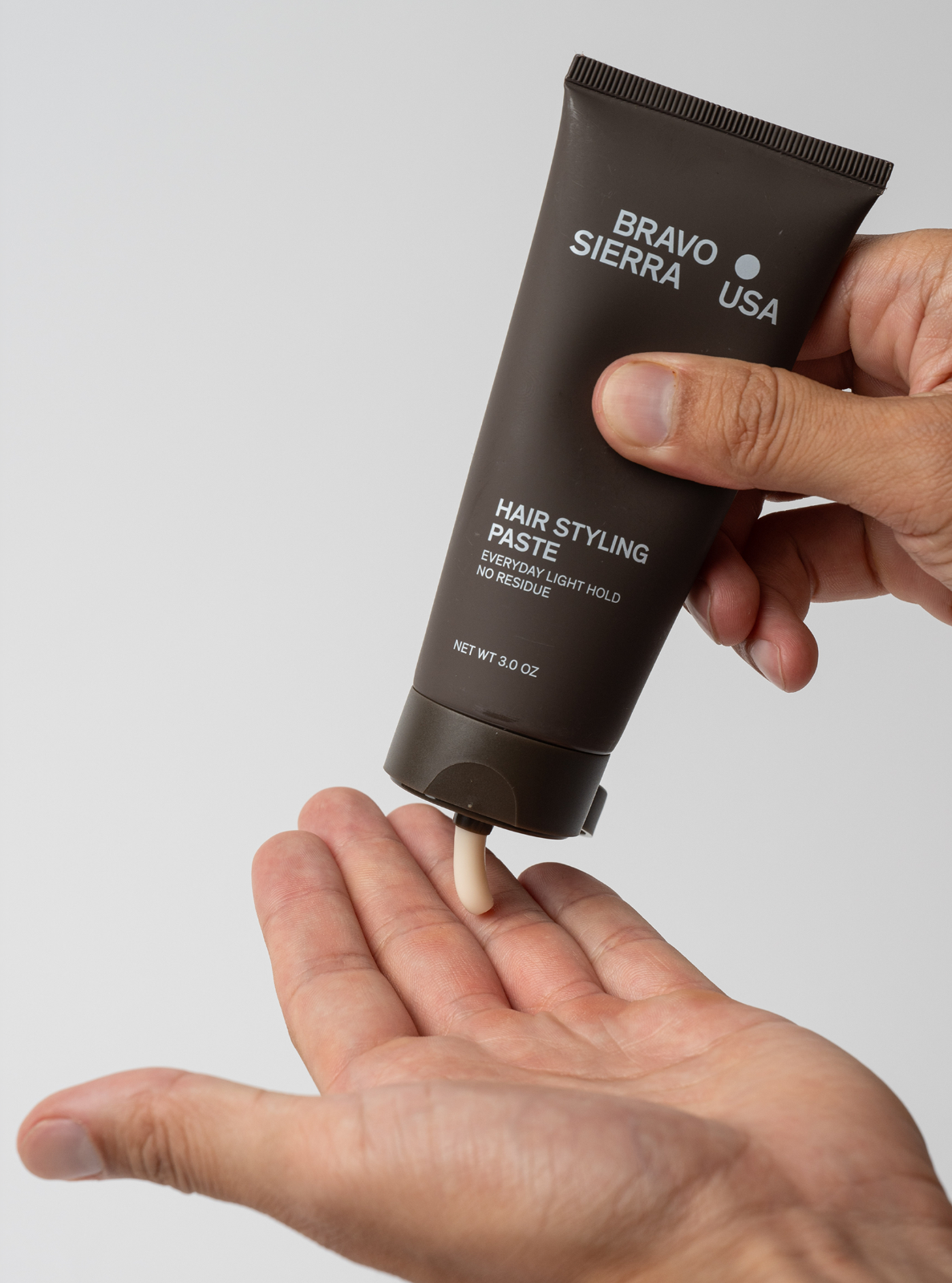 Hand holding a tube of Bravo Sierra USA hair styling paste against a plain background