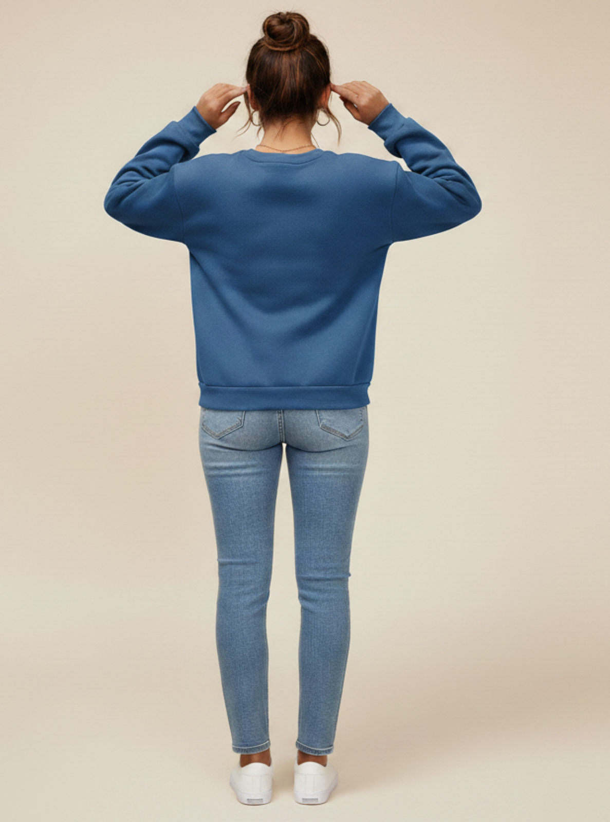 Person wearing a blue sweatshirt and jeans on a beige background