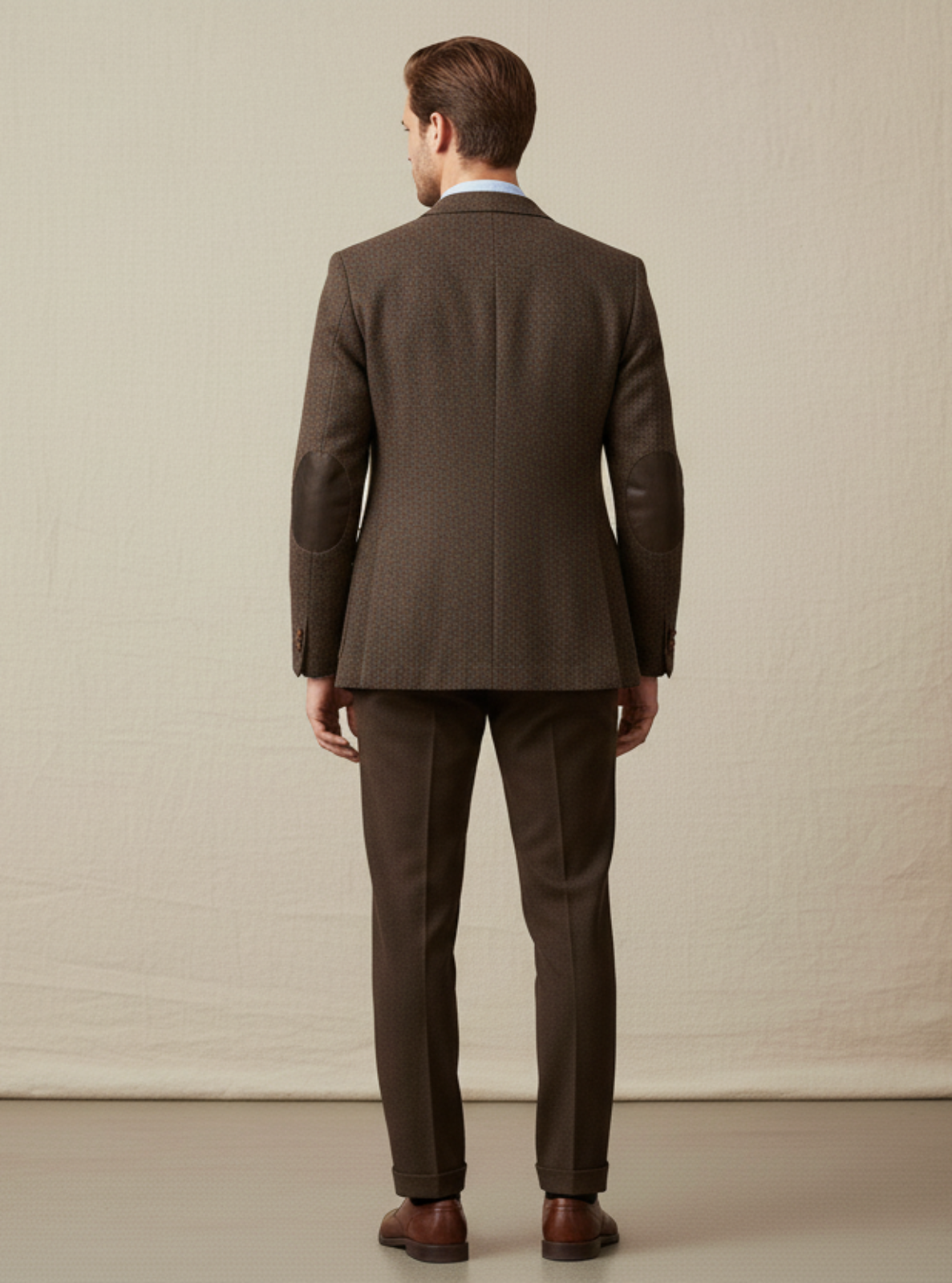 Man wearing a brown suit standing against a plain background