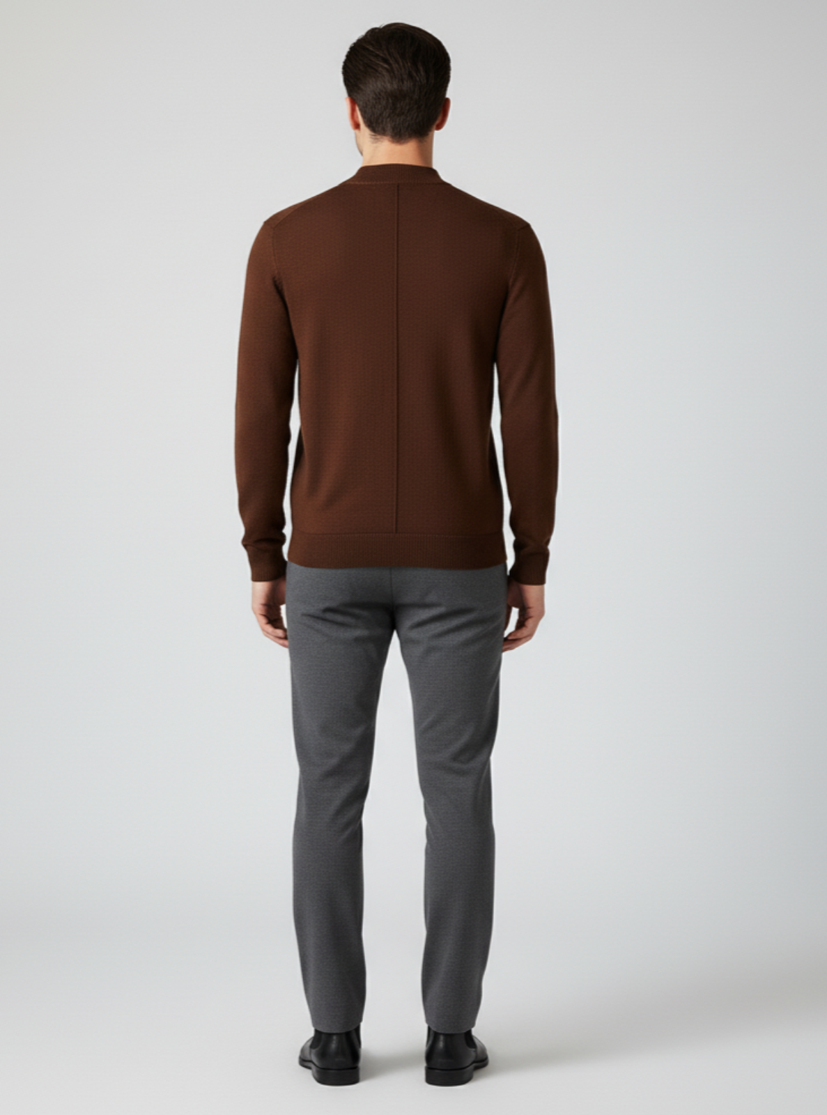 Man wearing a brown sweater and gray pants on a white background