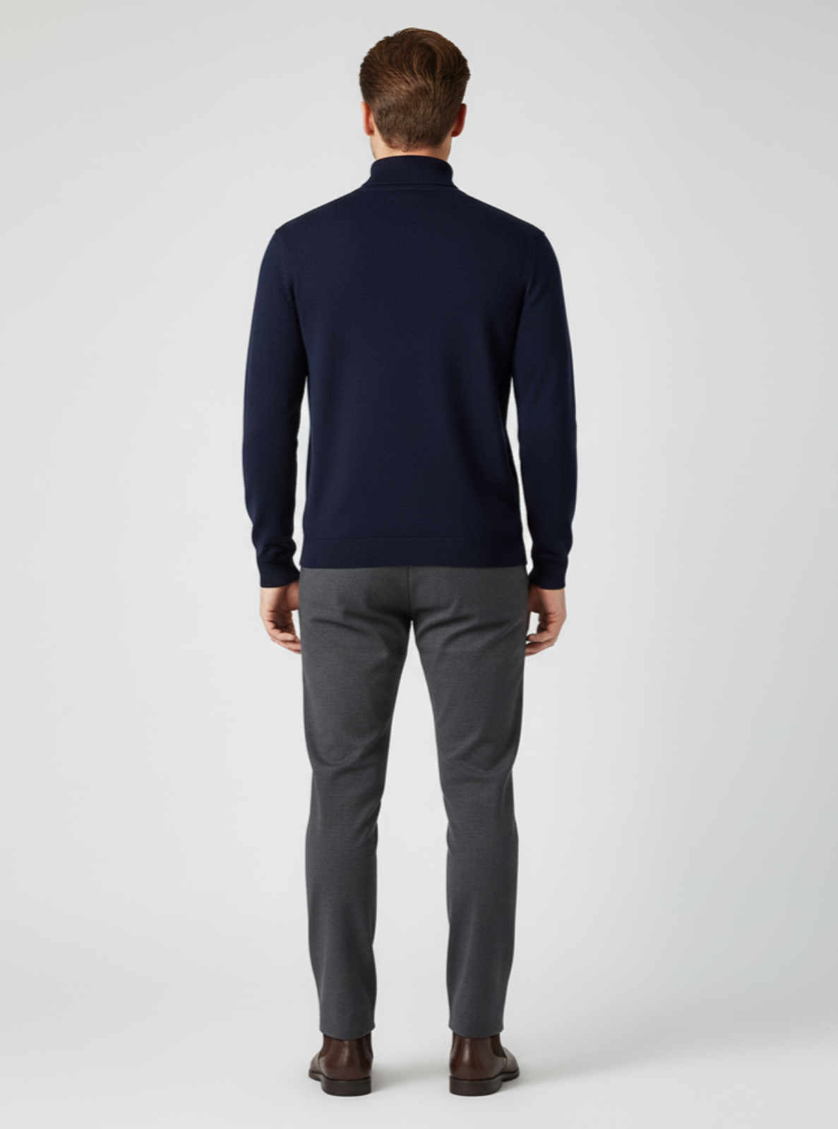 Man wearing a navy sweater and gray pants on a white background