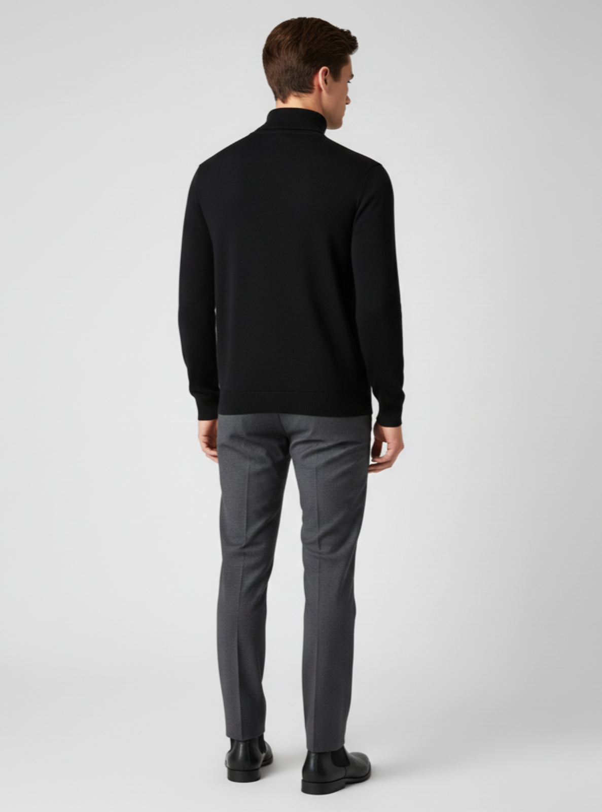 Man wearing a black turtleneck and gray pants on a white background