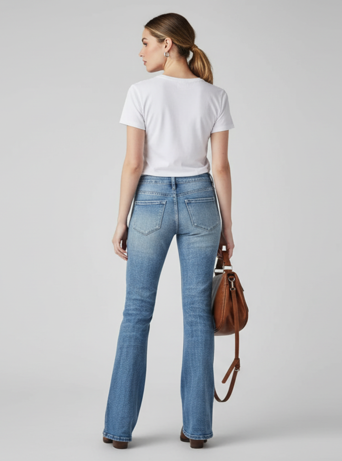 Woman wearing blue jeans and a white t-shirt on a gray background