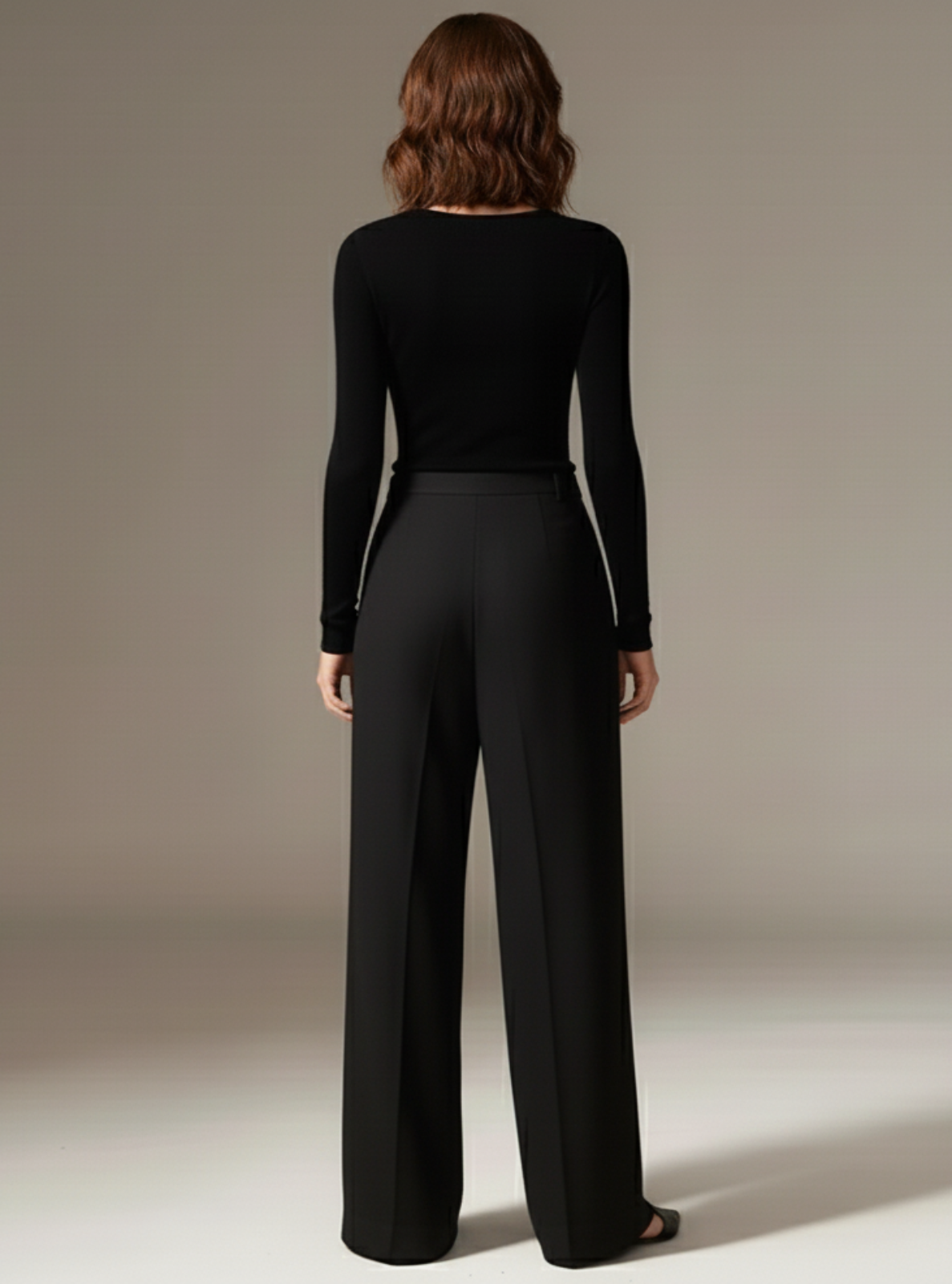 Person wearing a black long-sleeve top and black pants against a neutral background