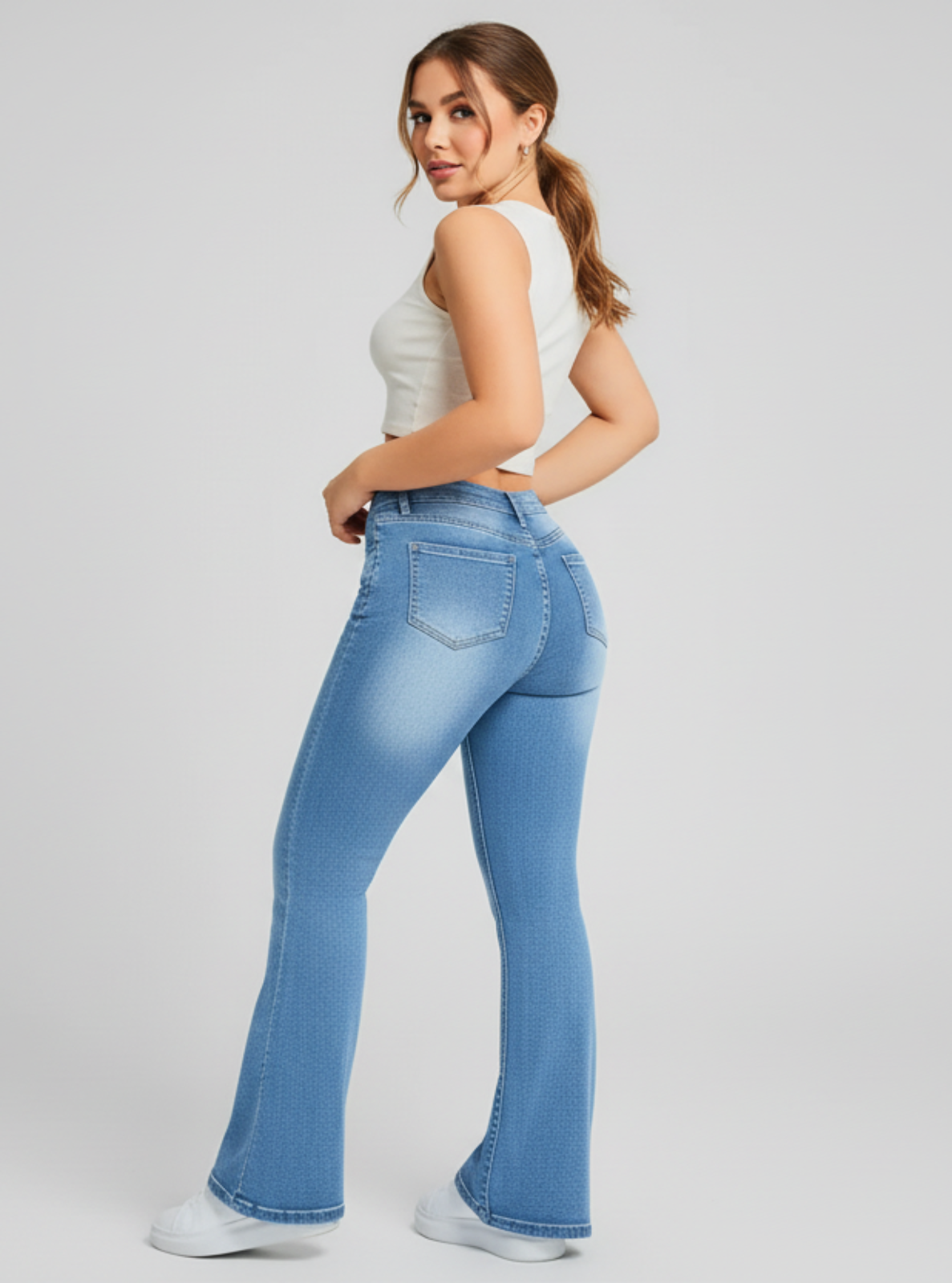 Woman wearing blue jeans and a white top on a plain background