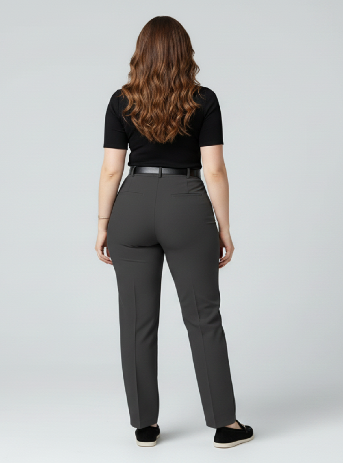 Woman wearing gray pants and a black top on a white background