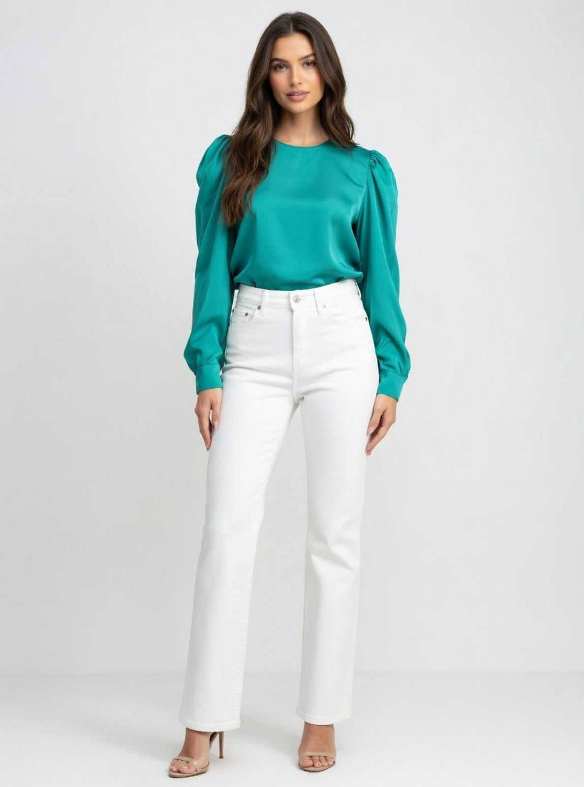 Woman wearing a teal blouse and white pants on a white background
