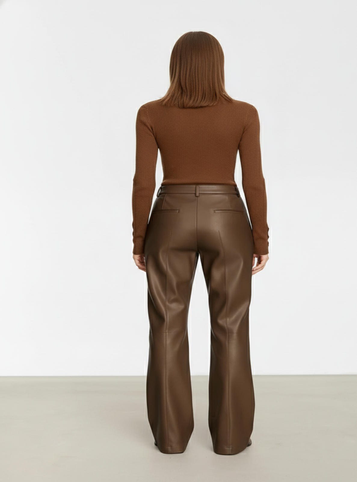 Person wearing brown leather pants and a matching top on a white background