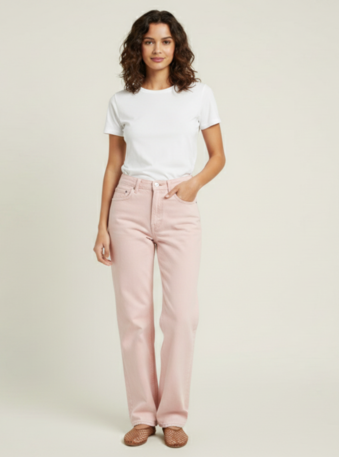 Woman wearing a white t-shirt and pink pants on a beige background
