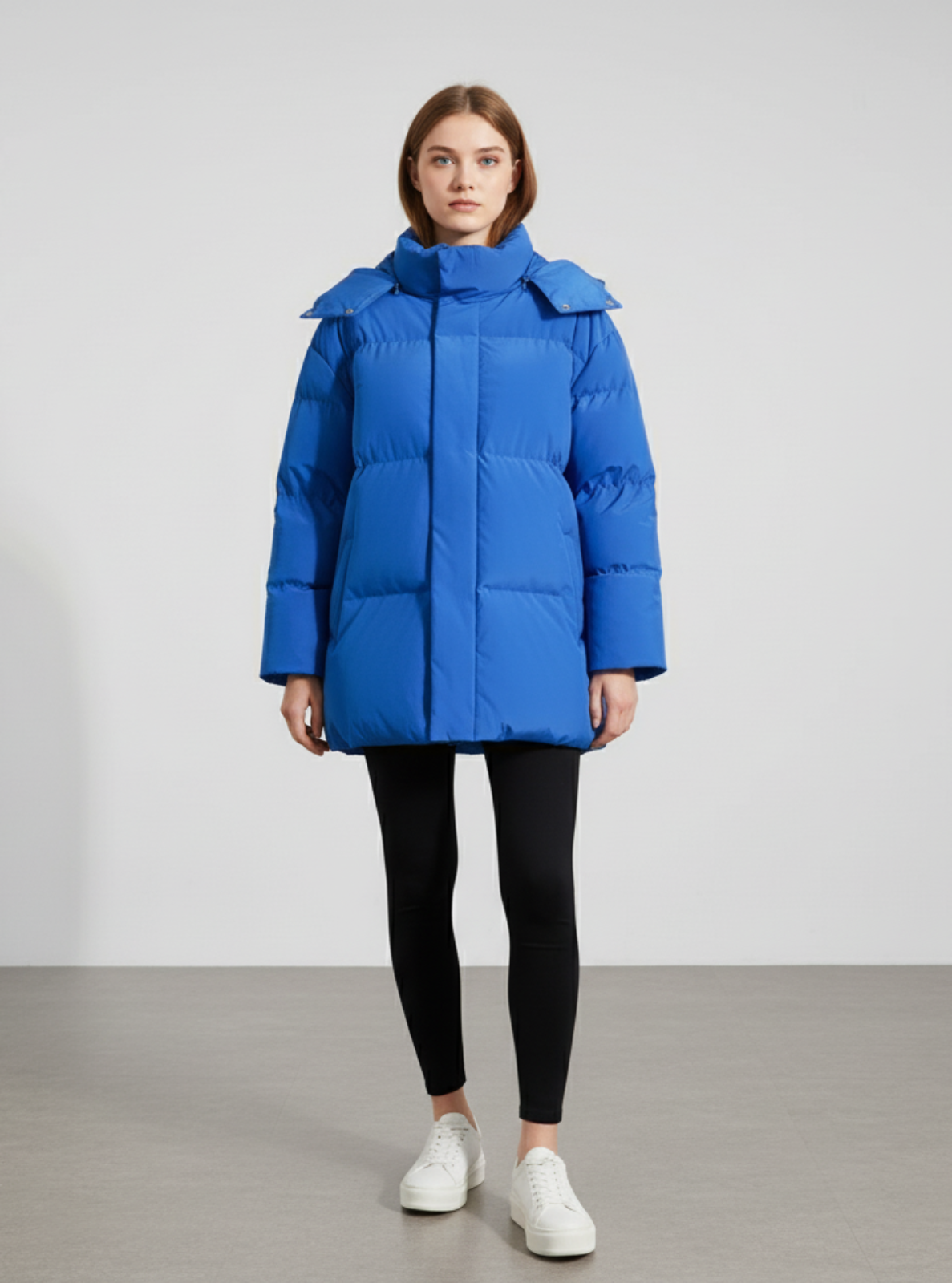 Person wearing a blue puffer coat against a plain background