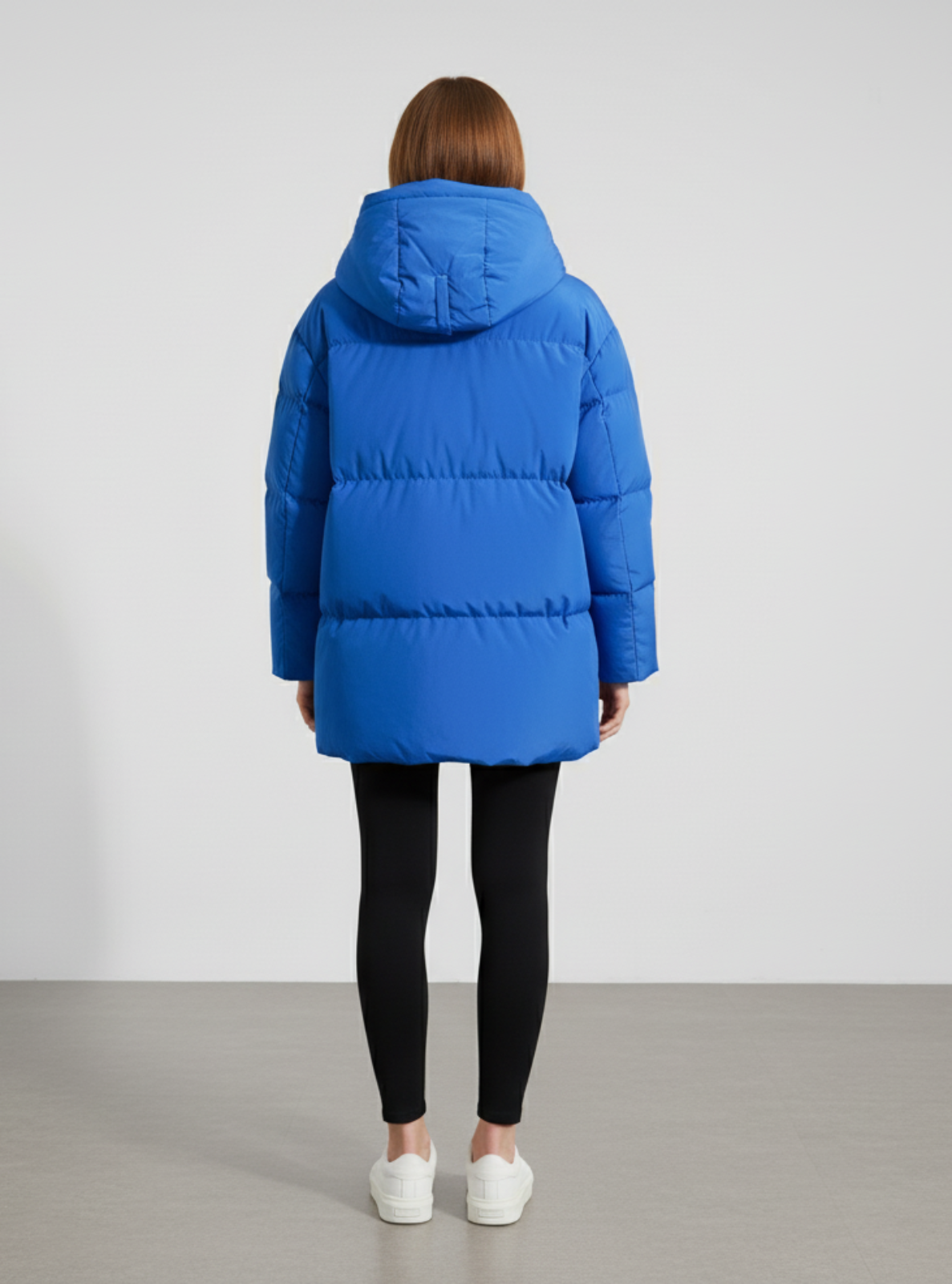 Person wearing a blue puffer coat on a plain background