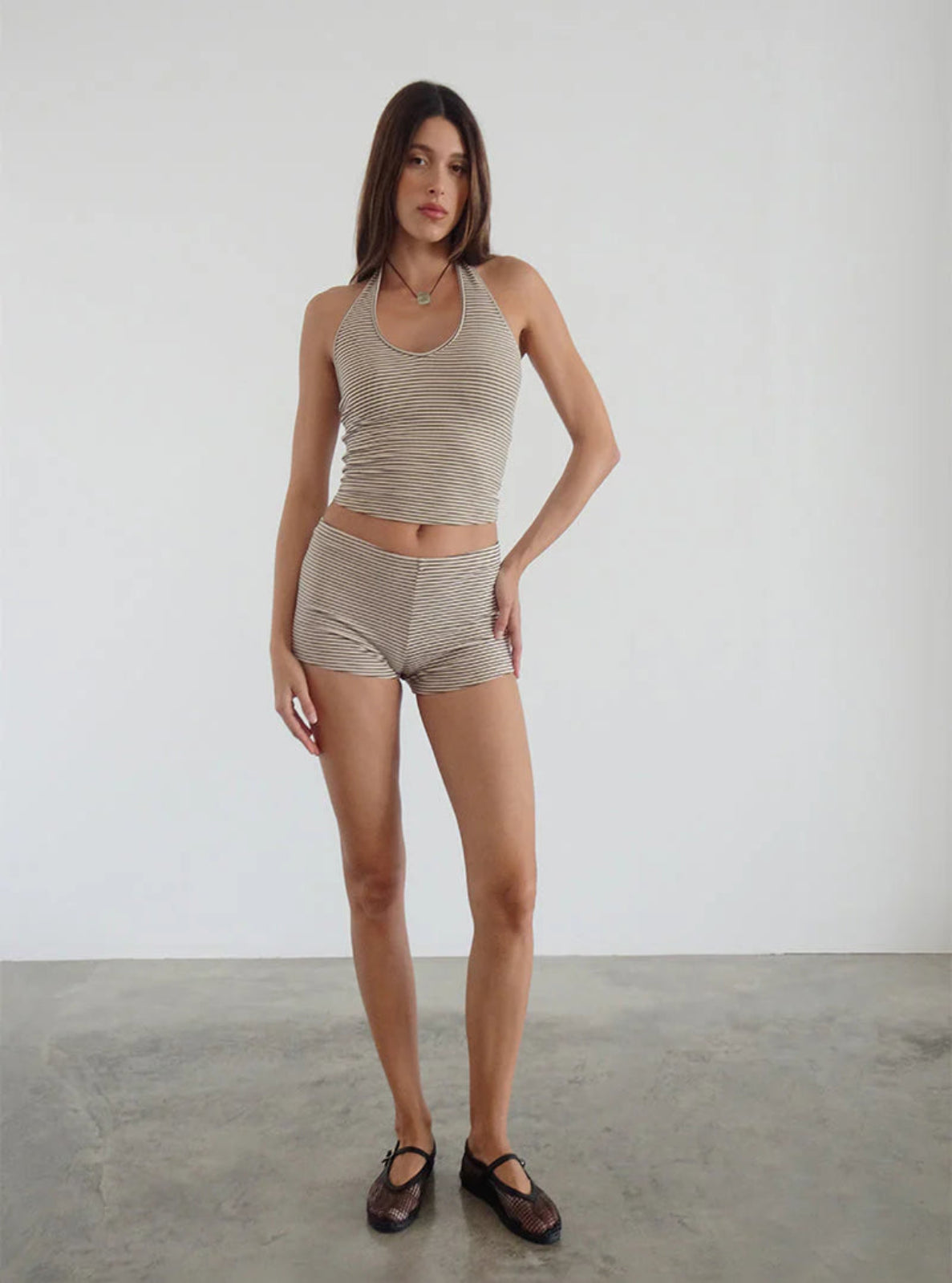 Woman wearing a beige tank top and shorts set on a plain background