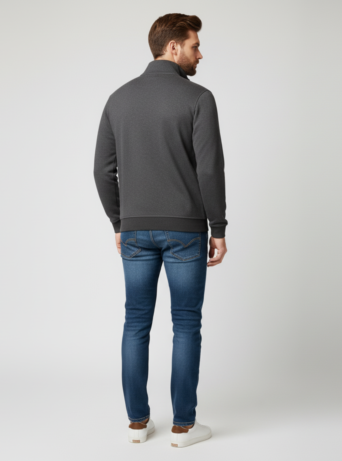 Man wearing a gray sweater and blue jeans on a white background