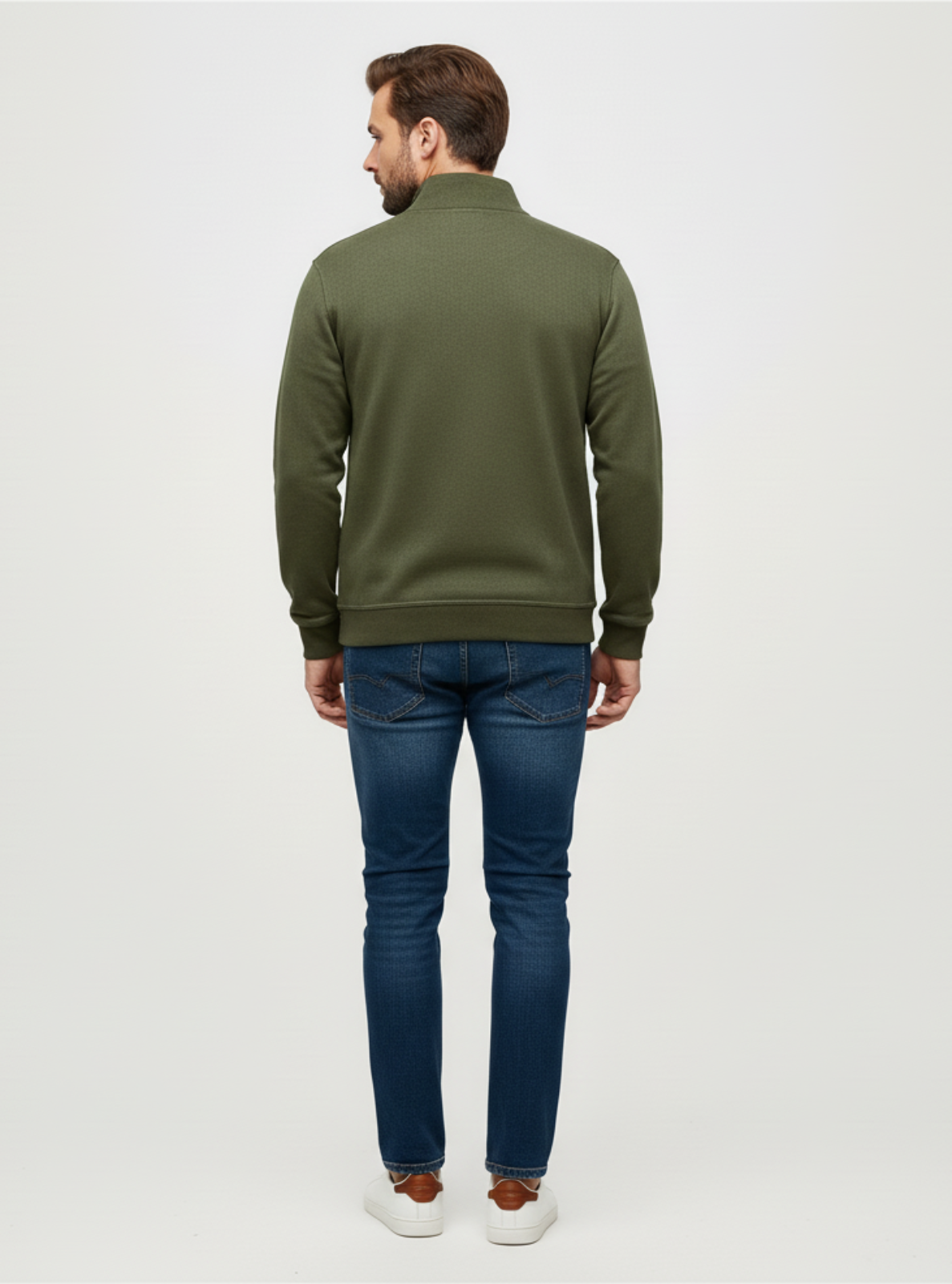 Man wearing a green sweater and blue jeans on a white background