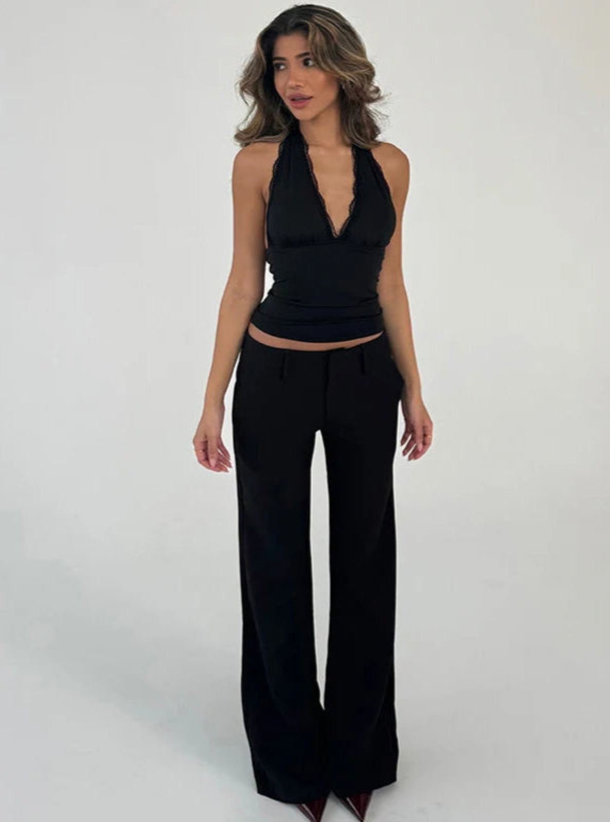 Woman wearing a black halter top and wide-leg pants on a white background