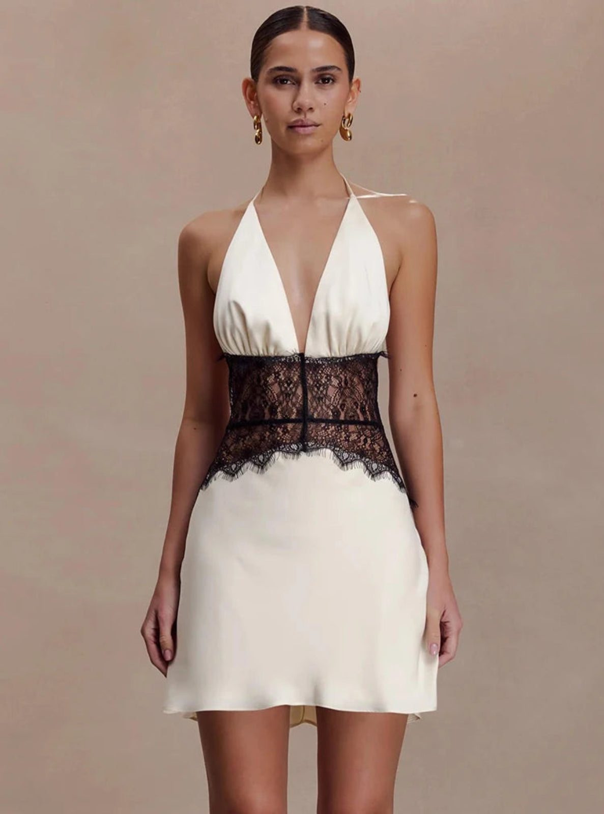 Woman wearing a white dress with black lace details on a beige background