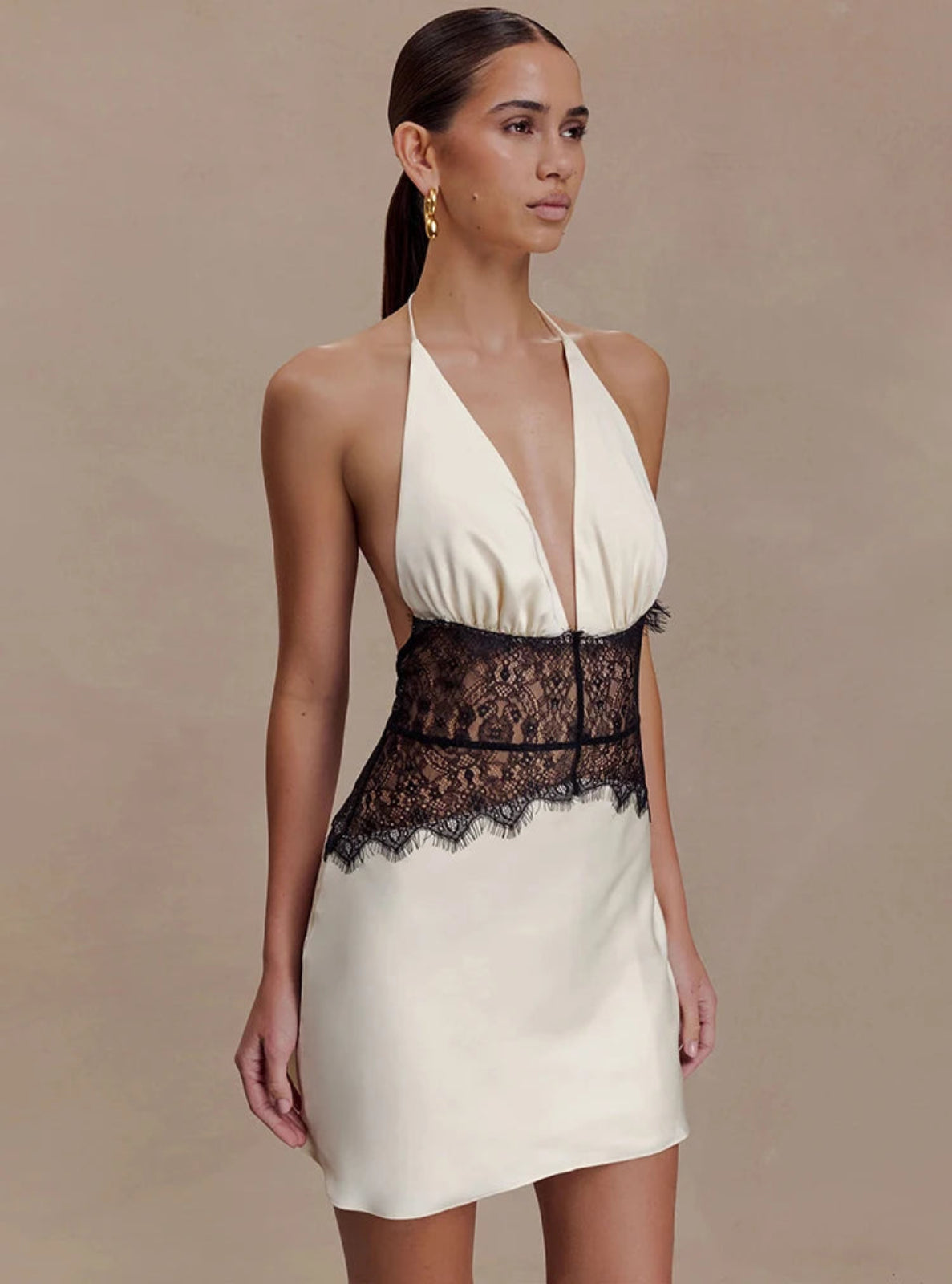 Woman wearing a white dress with black lace details on a beige background