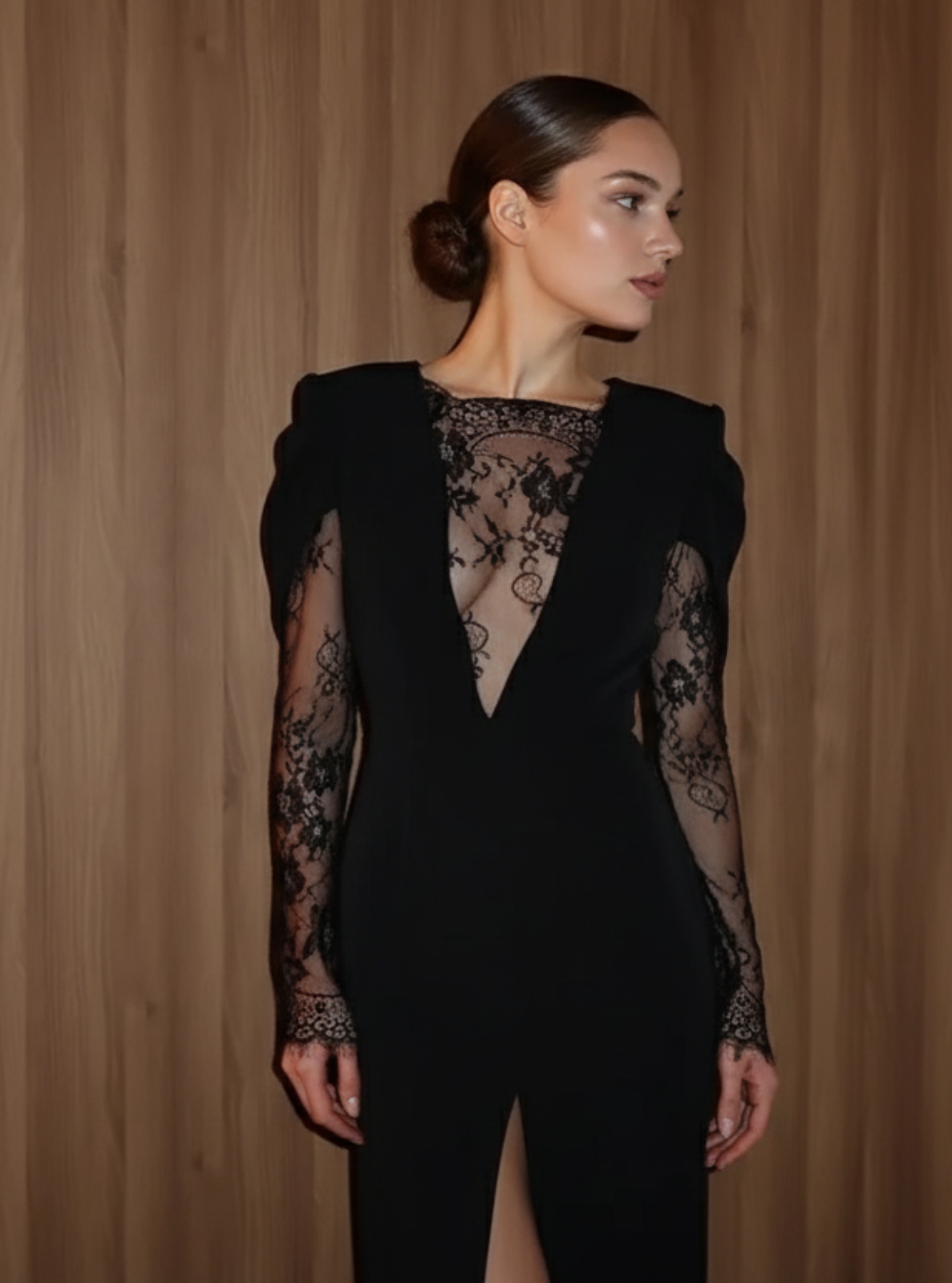 Woman wearing a black lace dress against a wooden paneled wall.