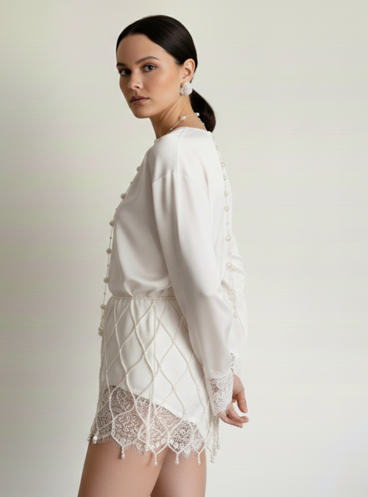 Woman wearing a white lace dress against a plain background