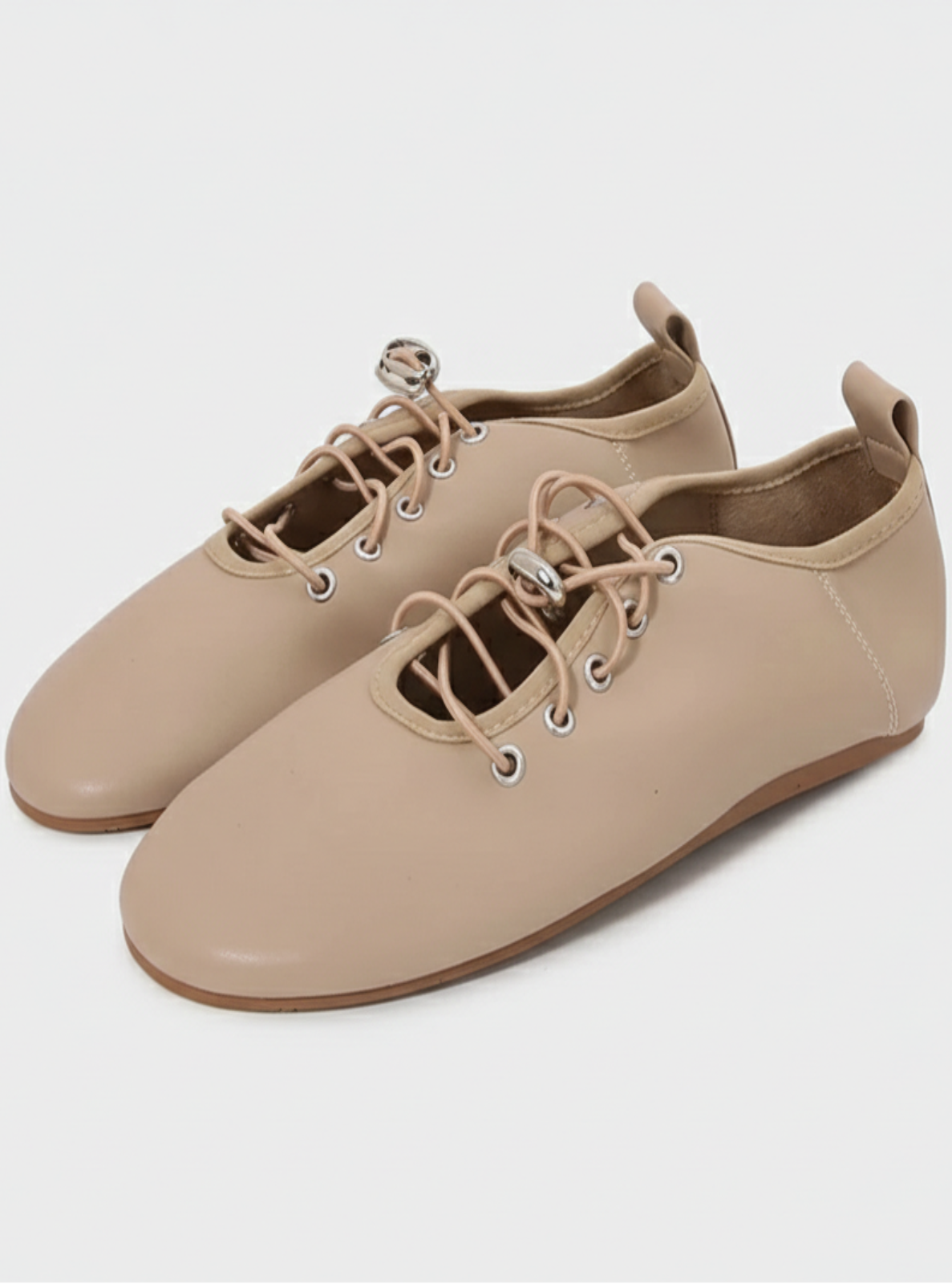 Pair of beige shoes with lace-up design on a white background