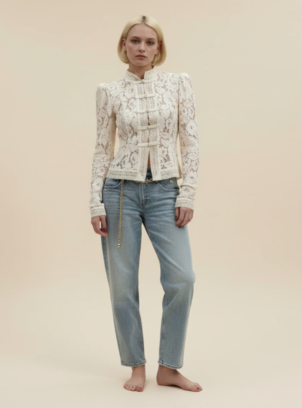 Woman wearing a white lace top and light blue jeans on a beige background