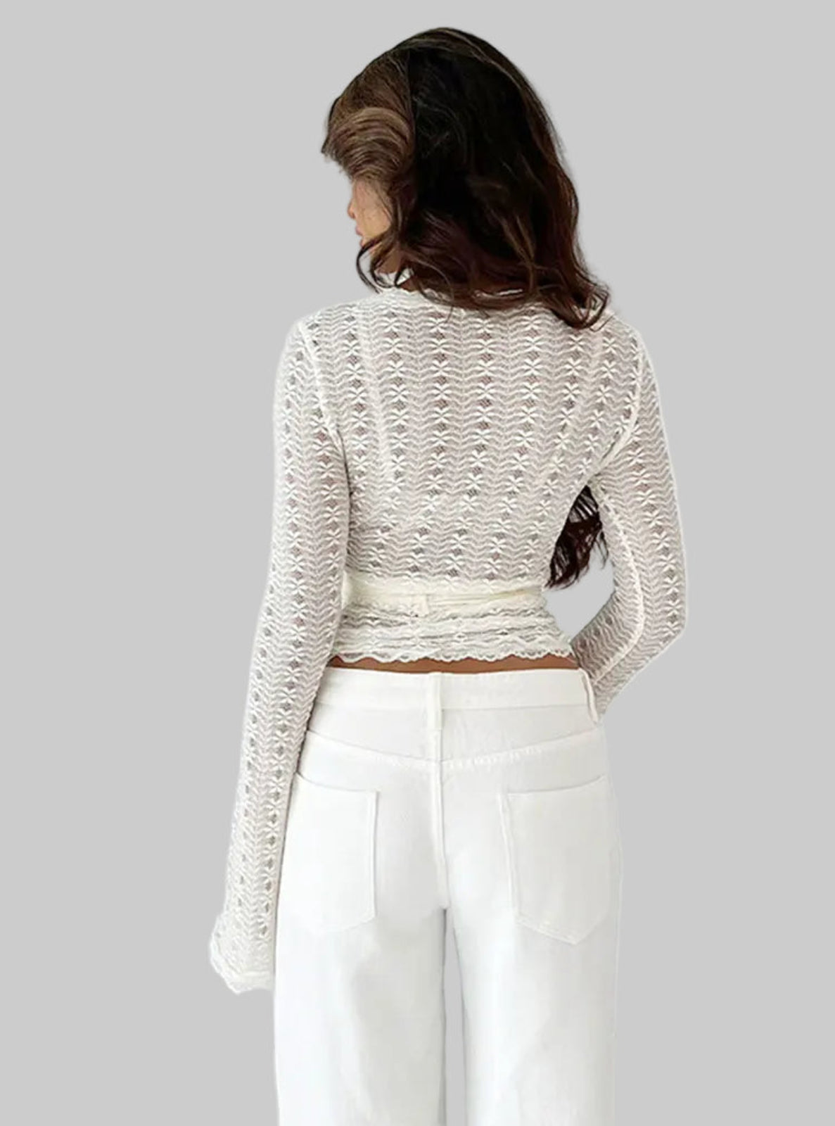 Person wearing a textured white top and white pants against a plain background