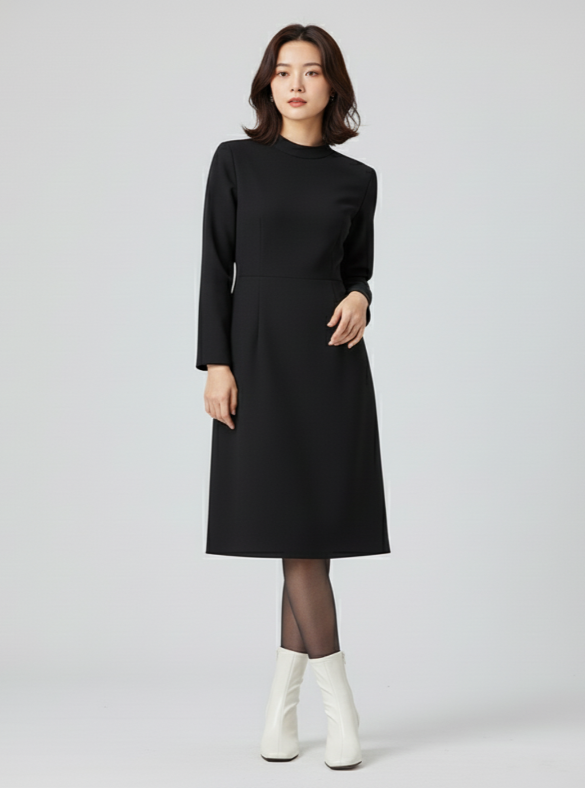 Woman wearing a black dress with white boots on a light gray background