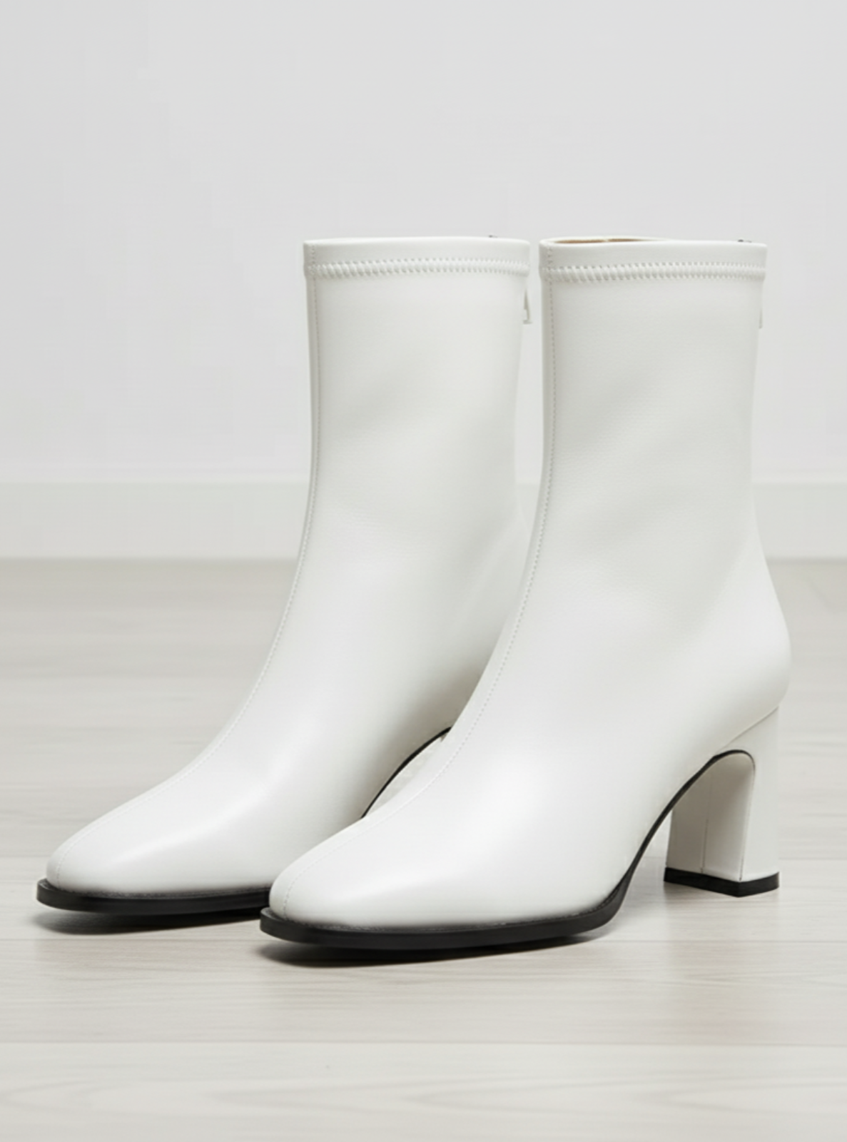 White ankle boots with a block heel on a light gray background