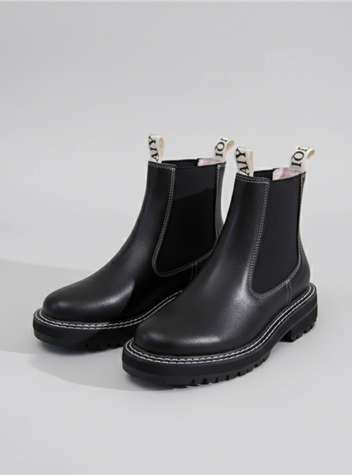 Black Chelsea boots on a light gray background