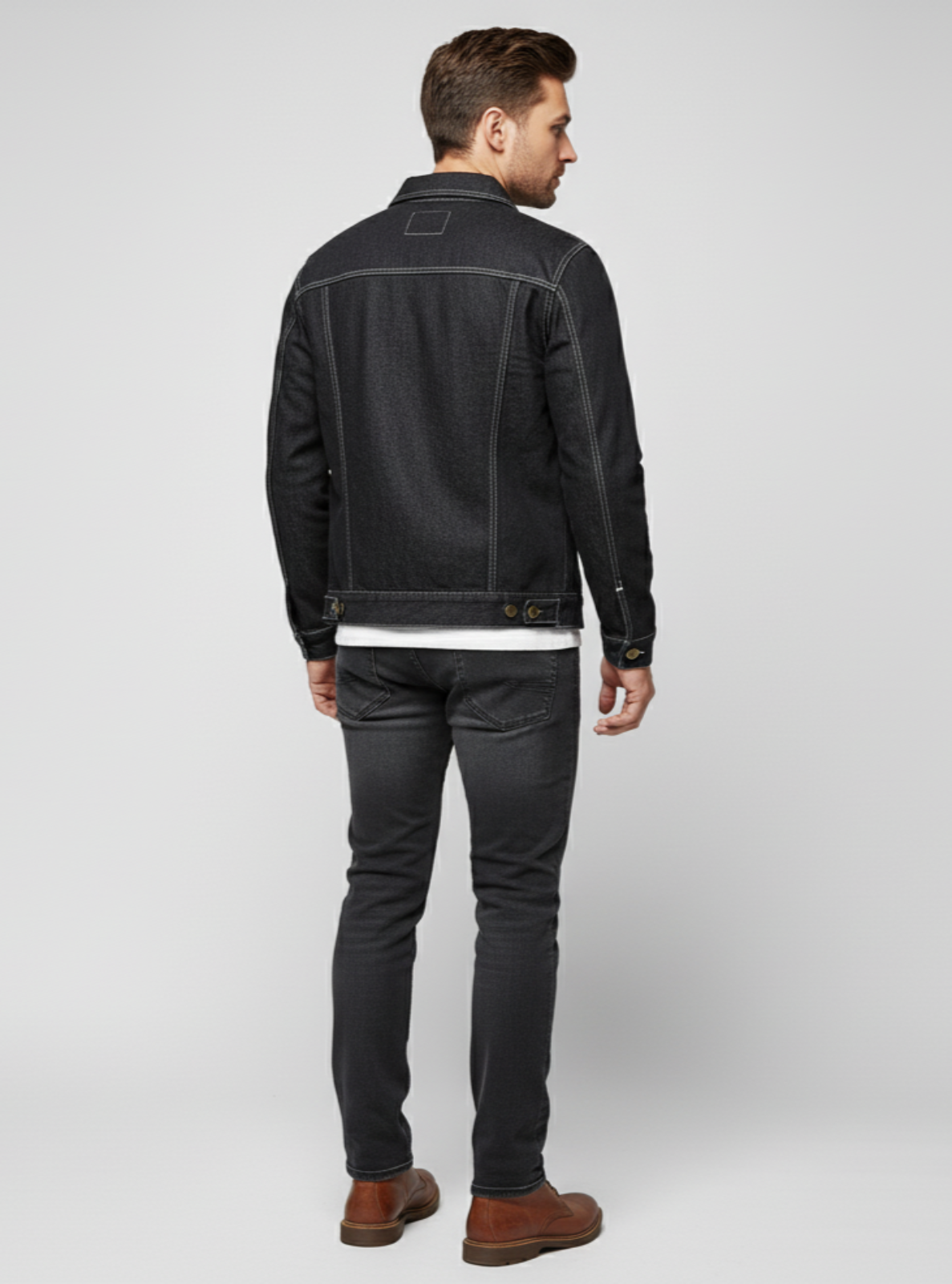 Man wearing a black denim jacket and jeans on a white background