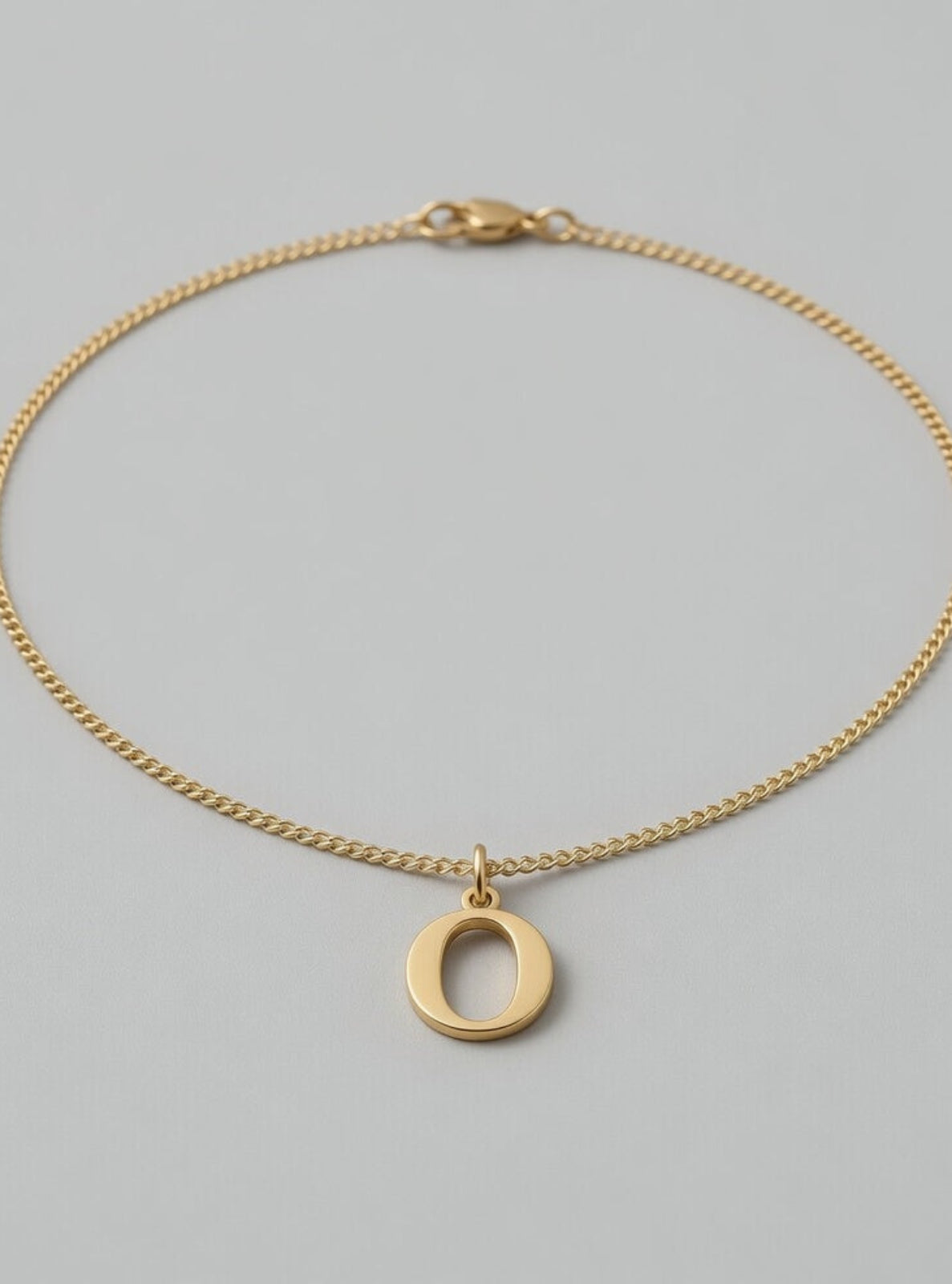 Gold necklace with a circular pendant on a gray background