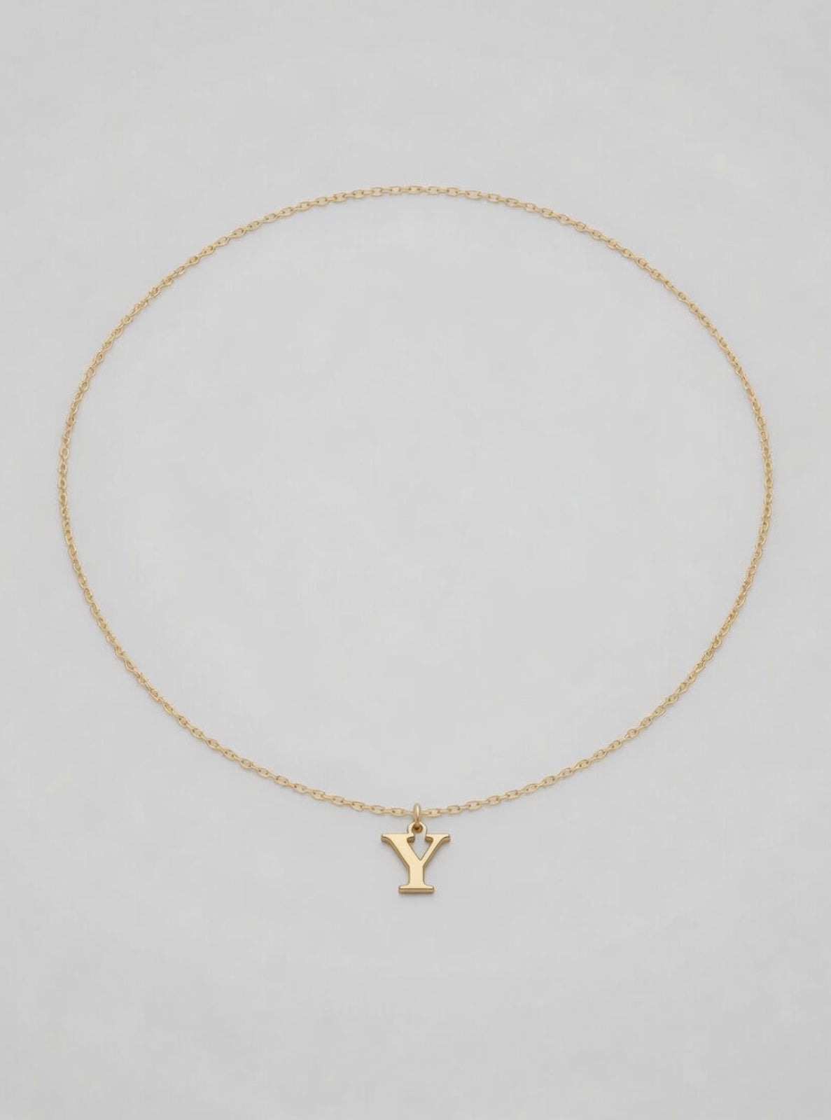 Gold necklace with a 'Y' pendant on a light gray background