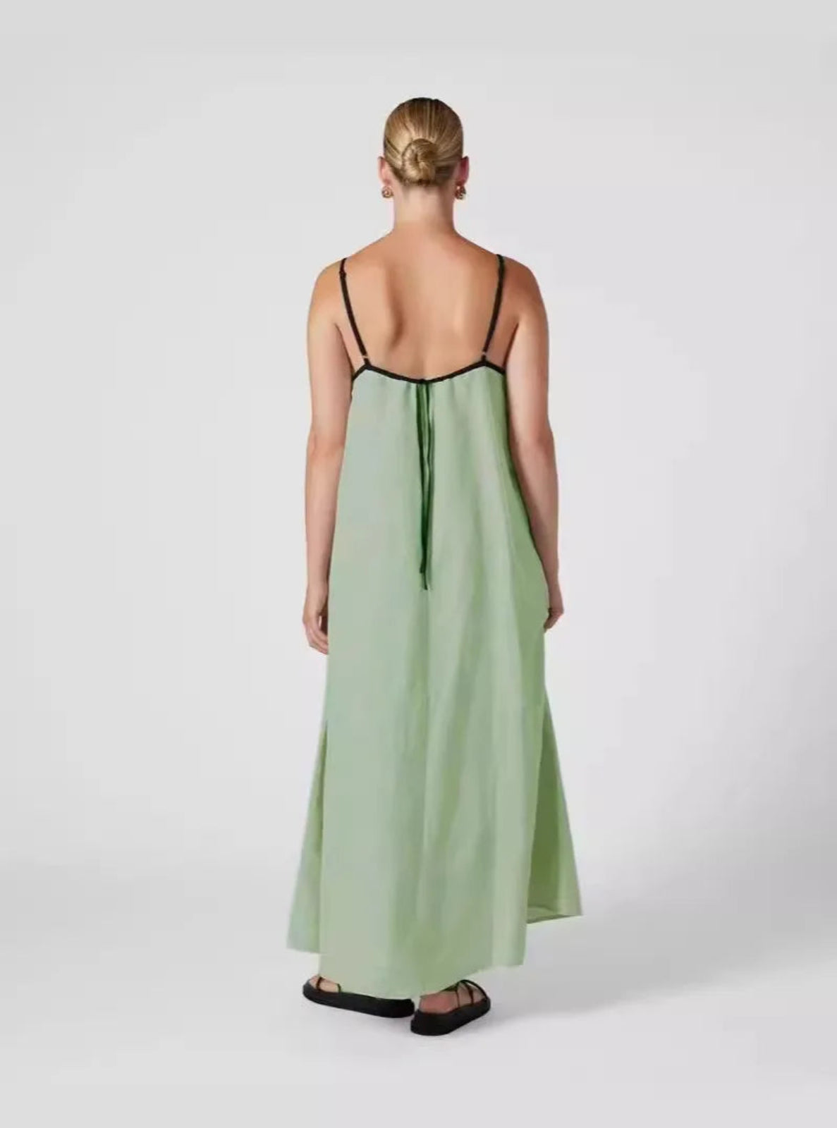 Woman wearing a green dress with thin straps on a white background