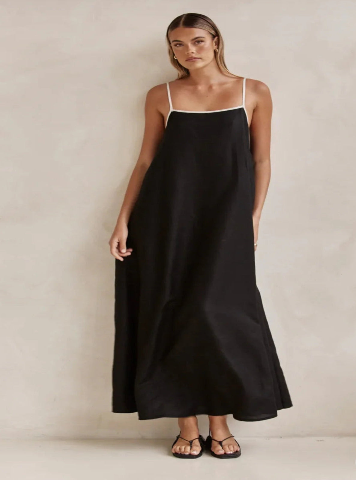 Woman wearing a black slip dress against a plain background