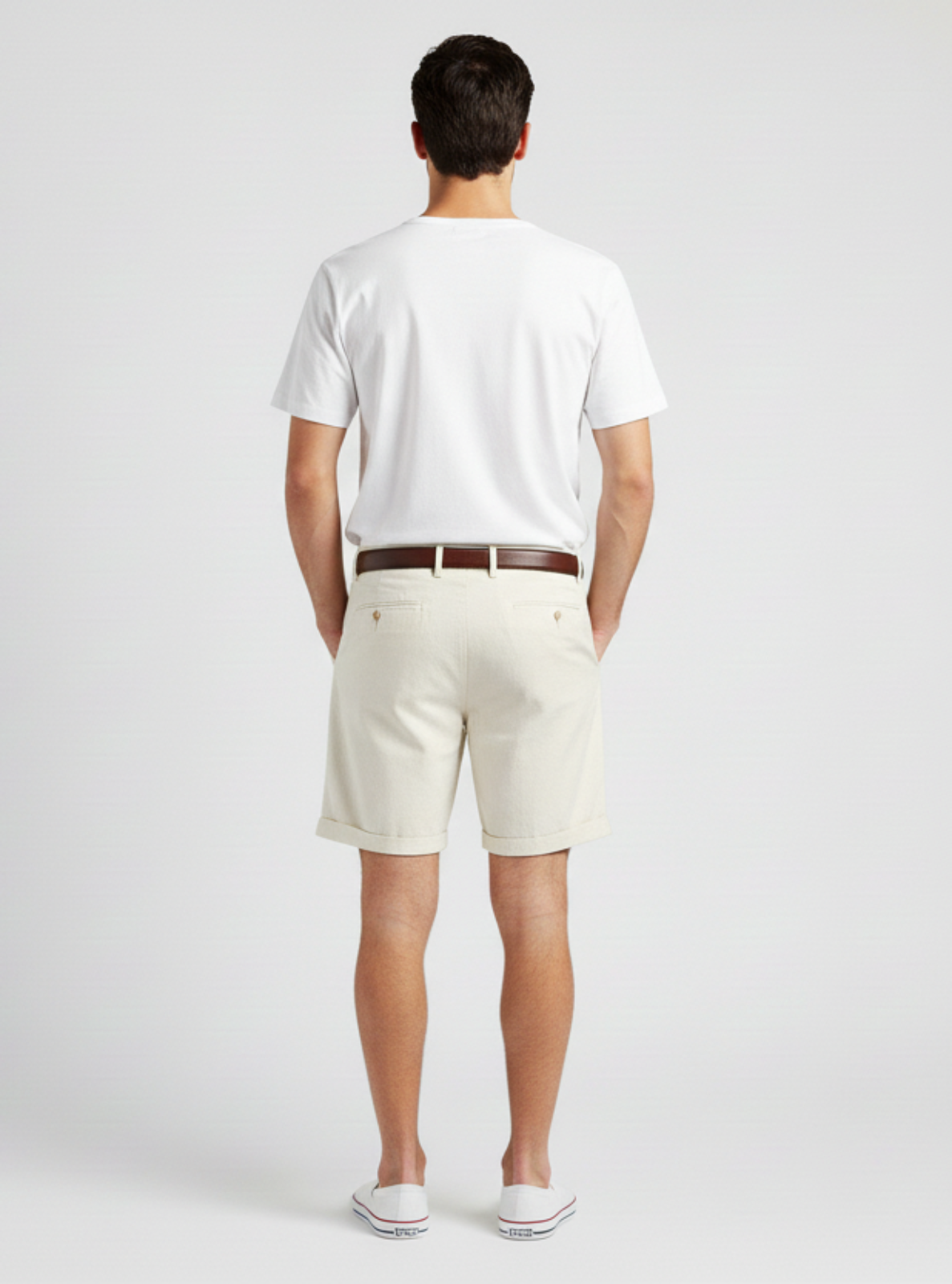 Man wearing a white t-shirt and beige shorts on a plain background