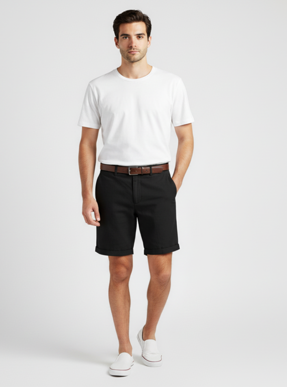 Man wearing a white t-shirt, black shorts, and white sneakers on a light gray background