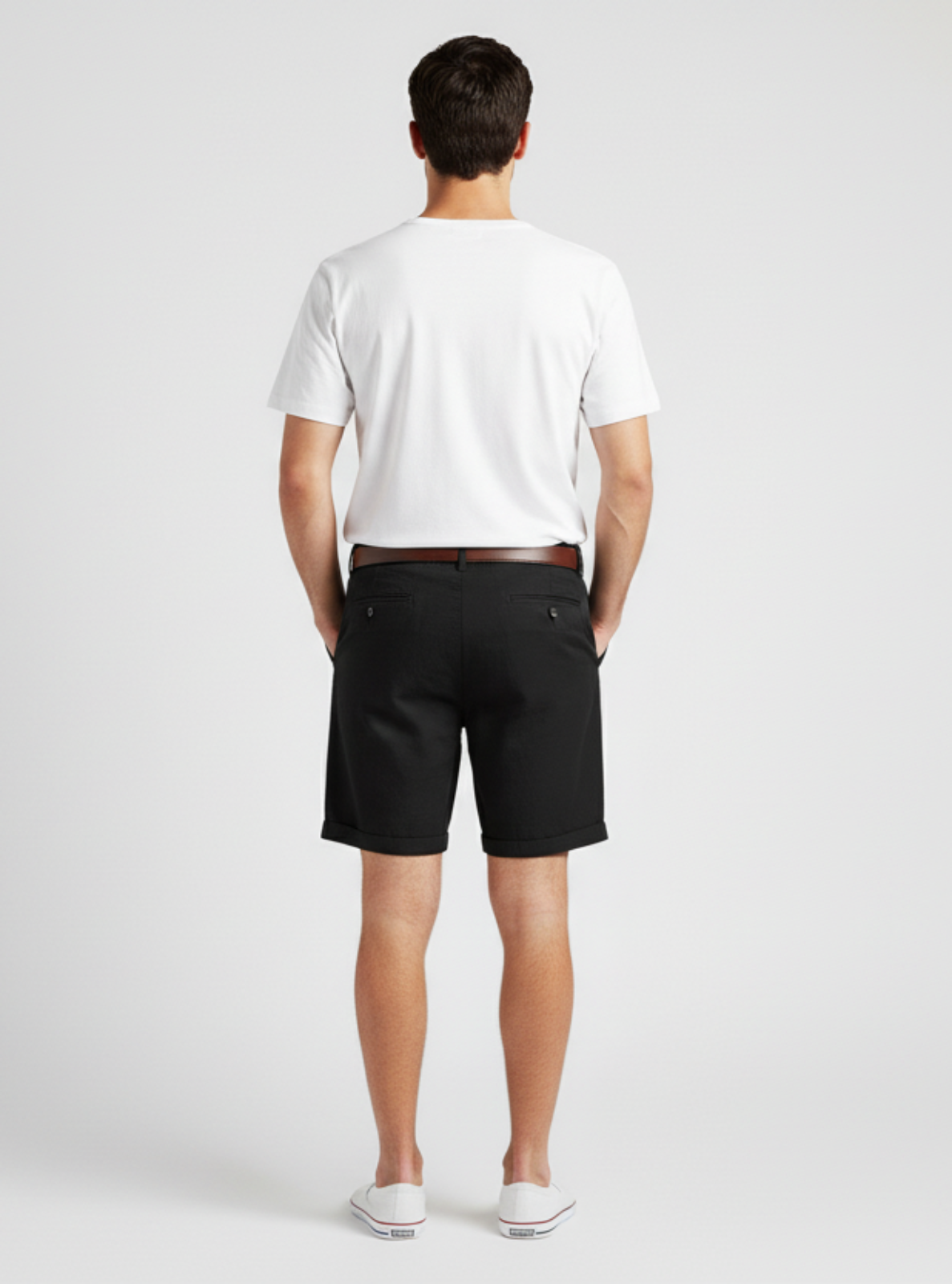 Man wearing a white t-shirt and black shorts on a plain background