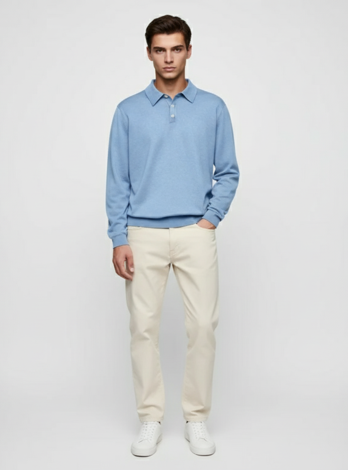 Man wearing a light blue sweater and white pants on a plain background