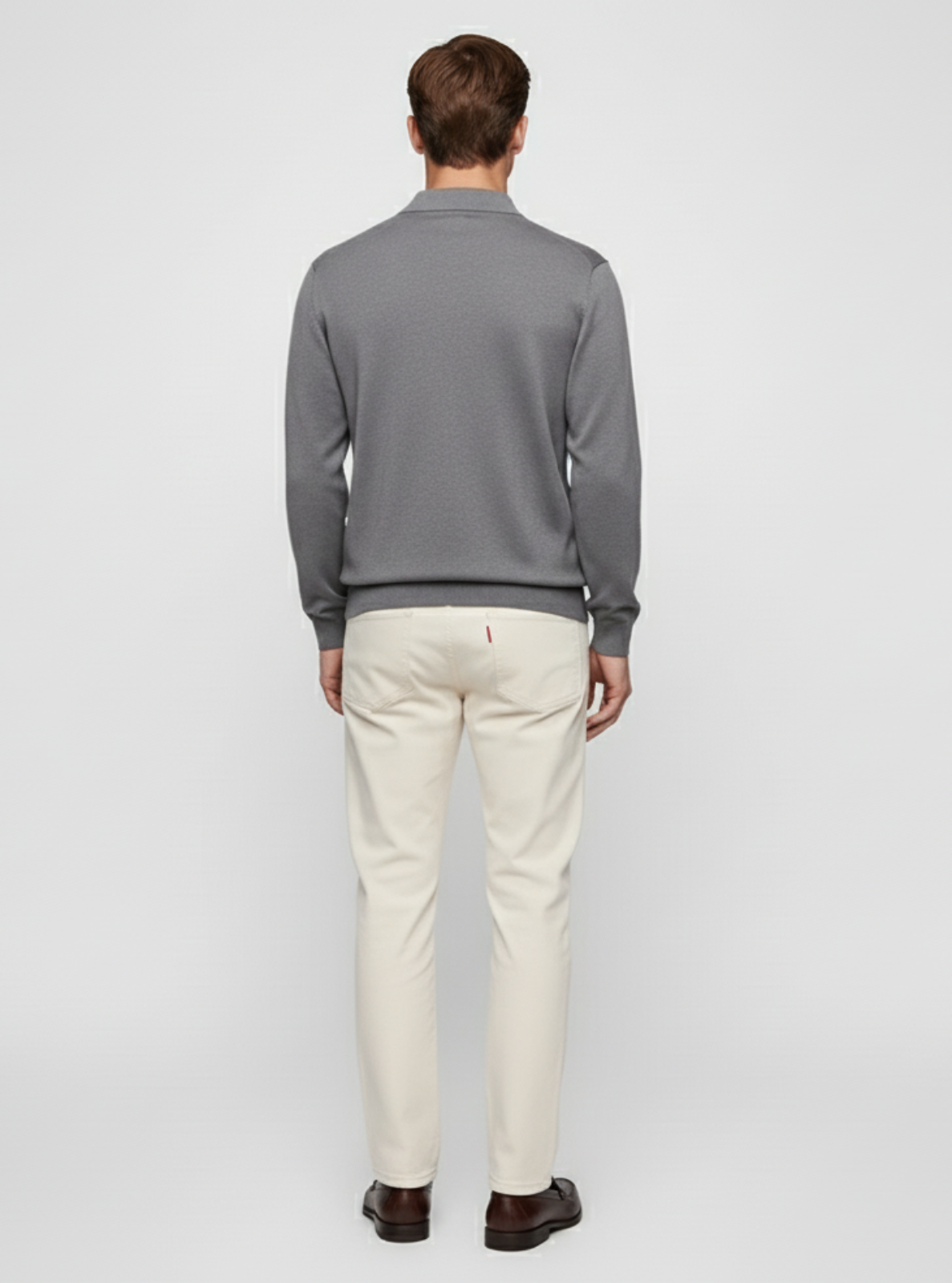 Man wearing a gray sweater and white pants on a light gray background