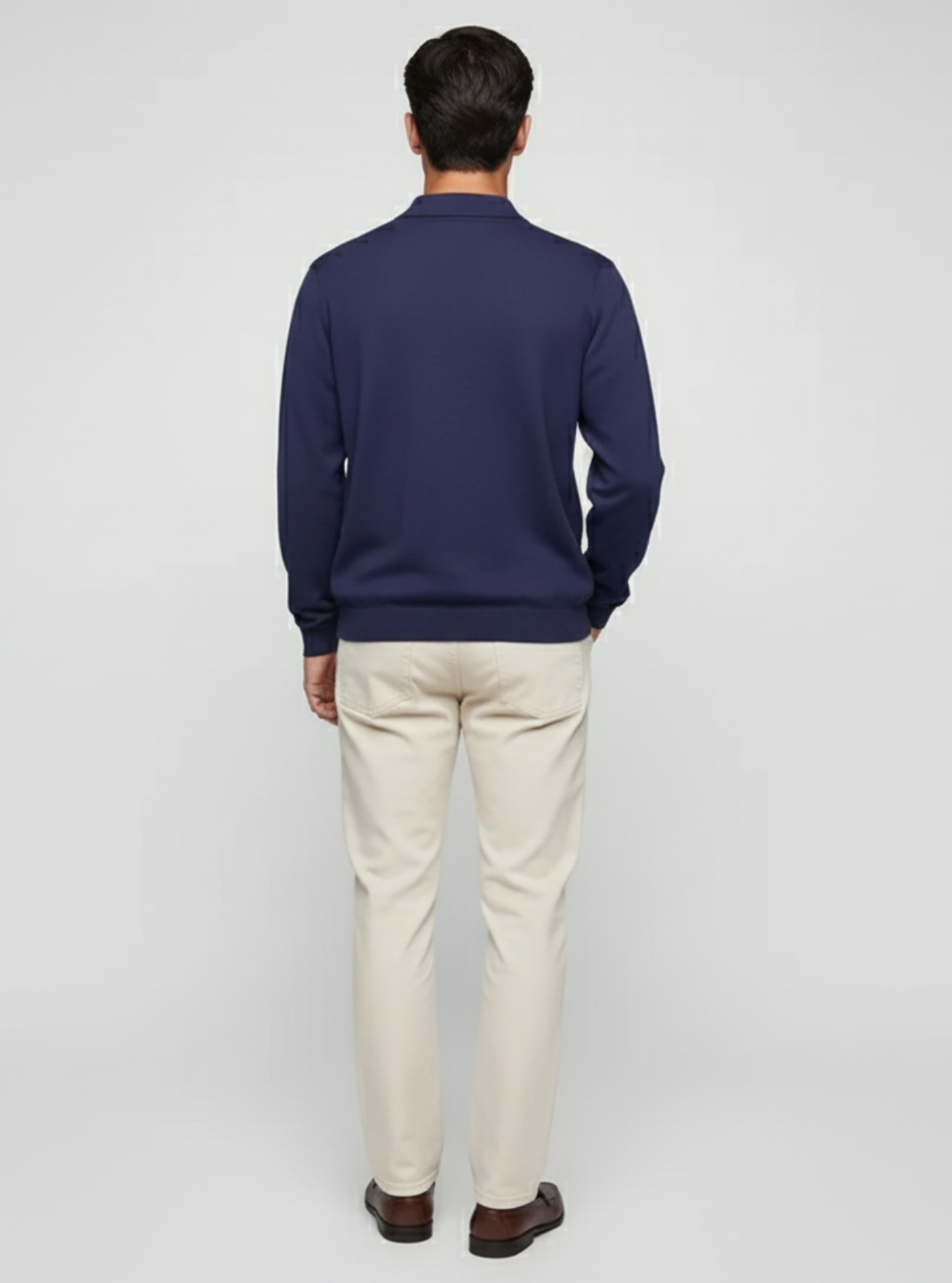 Man wearing a navy sweater and beige pants on a light gray background