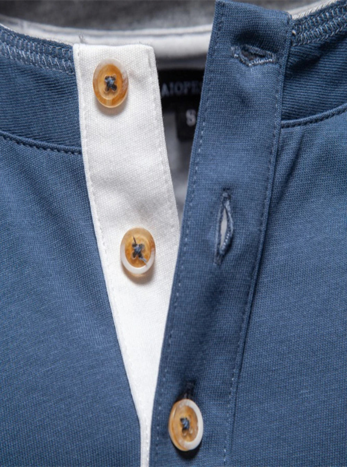 Close-up of a blue jacket with white shirt collar and wooden buttons.