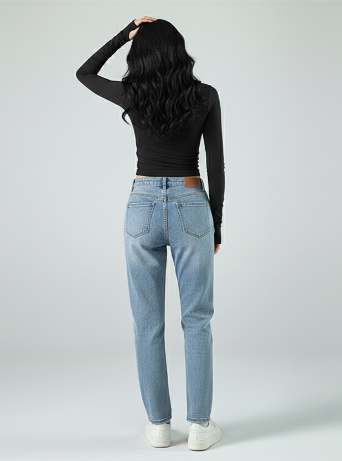 Person wearing light blue jeans and a black top on a white background