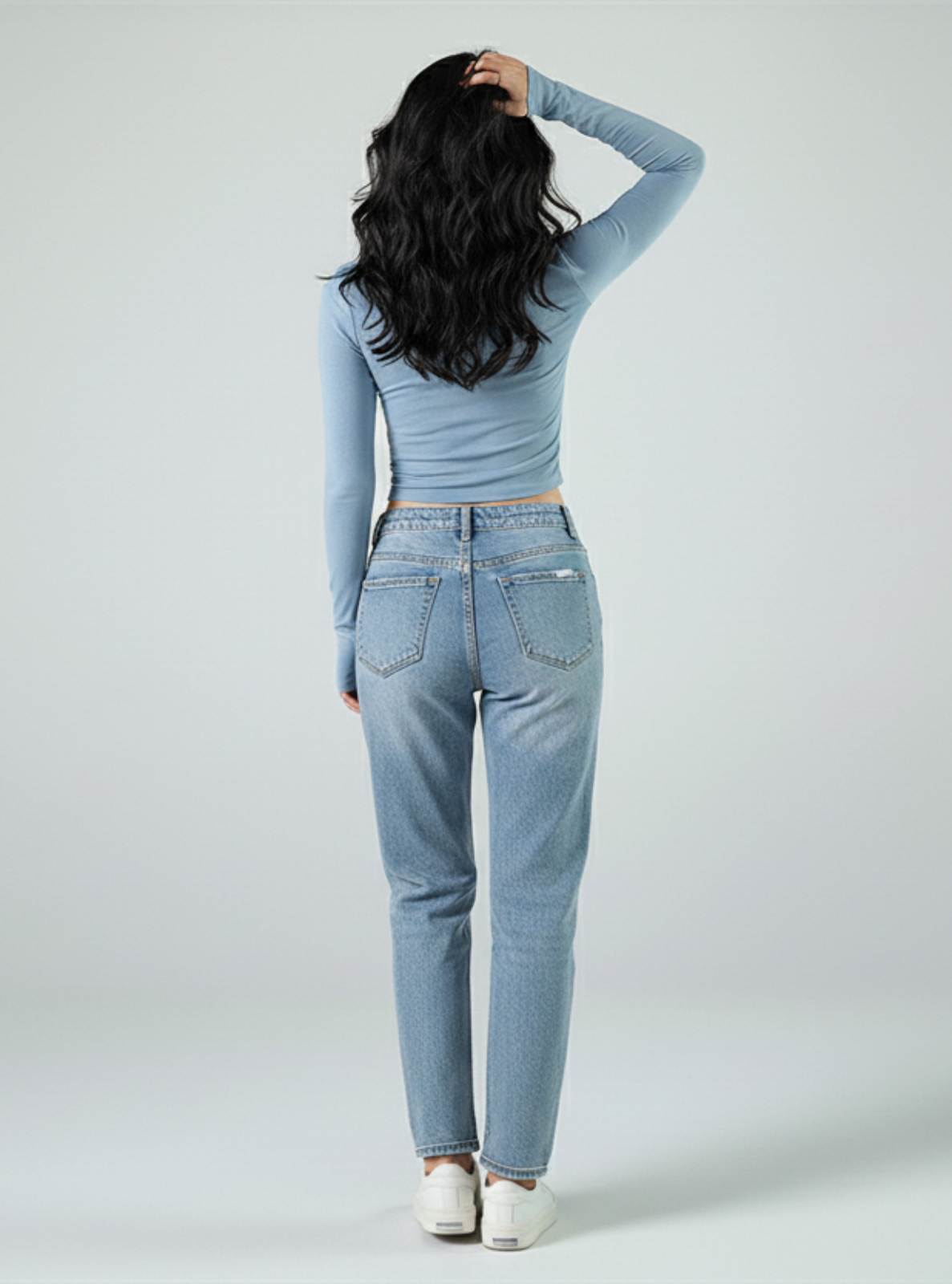 Person wearing a light blue top and jeans on a white background