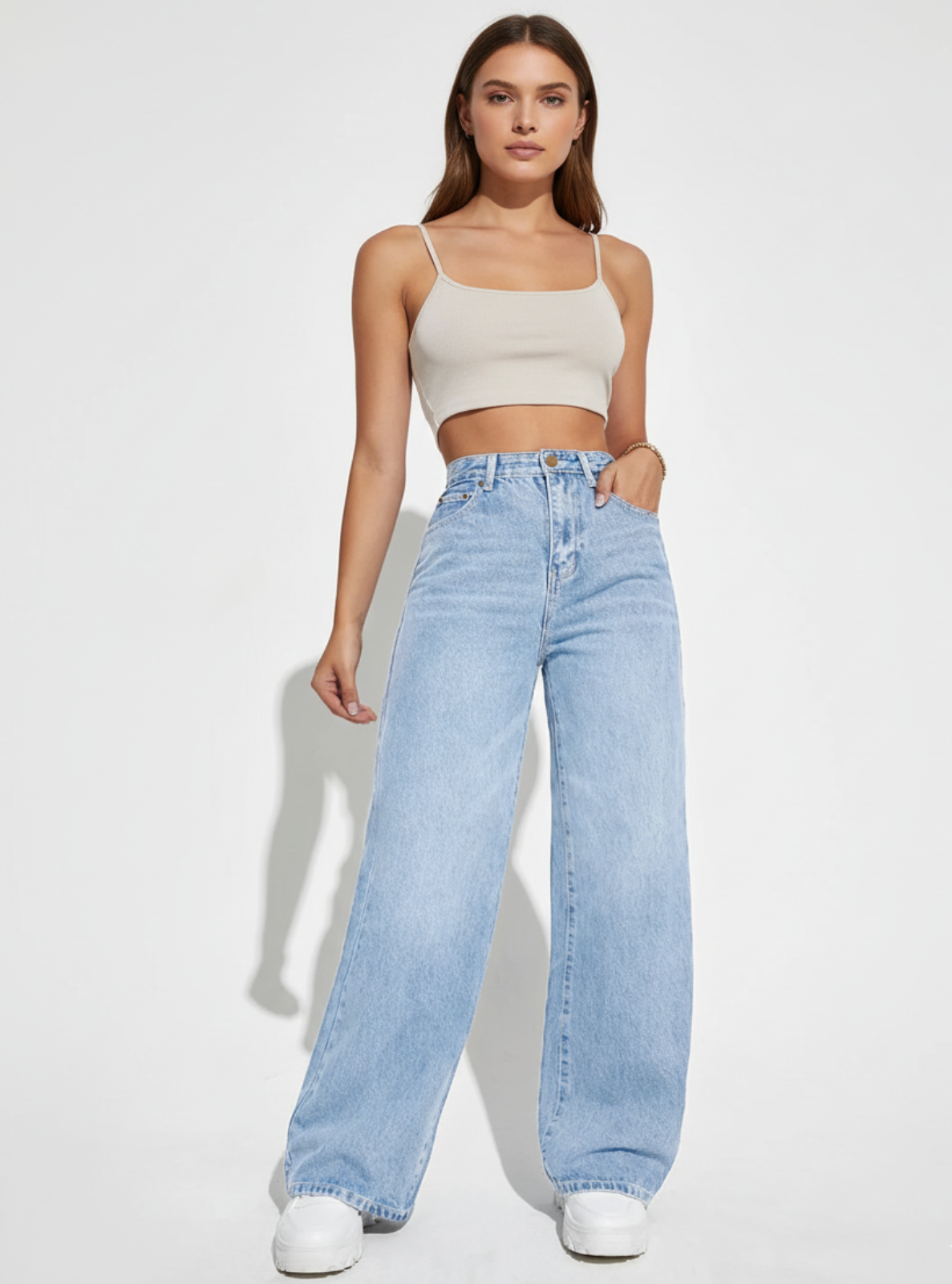 Woman wearing a beige top and light blue jeans on a white background