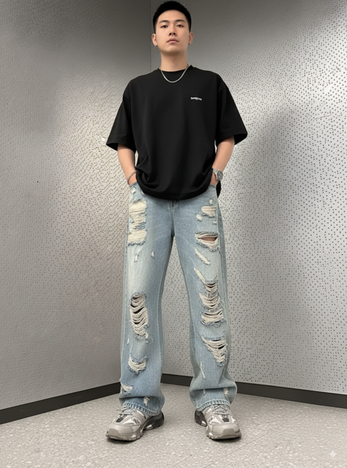 Person wearing a black t-shirt and light blue ripped jeans against a textured wall.