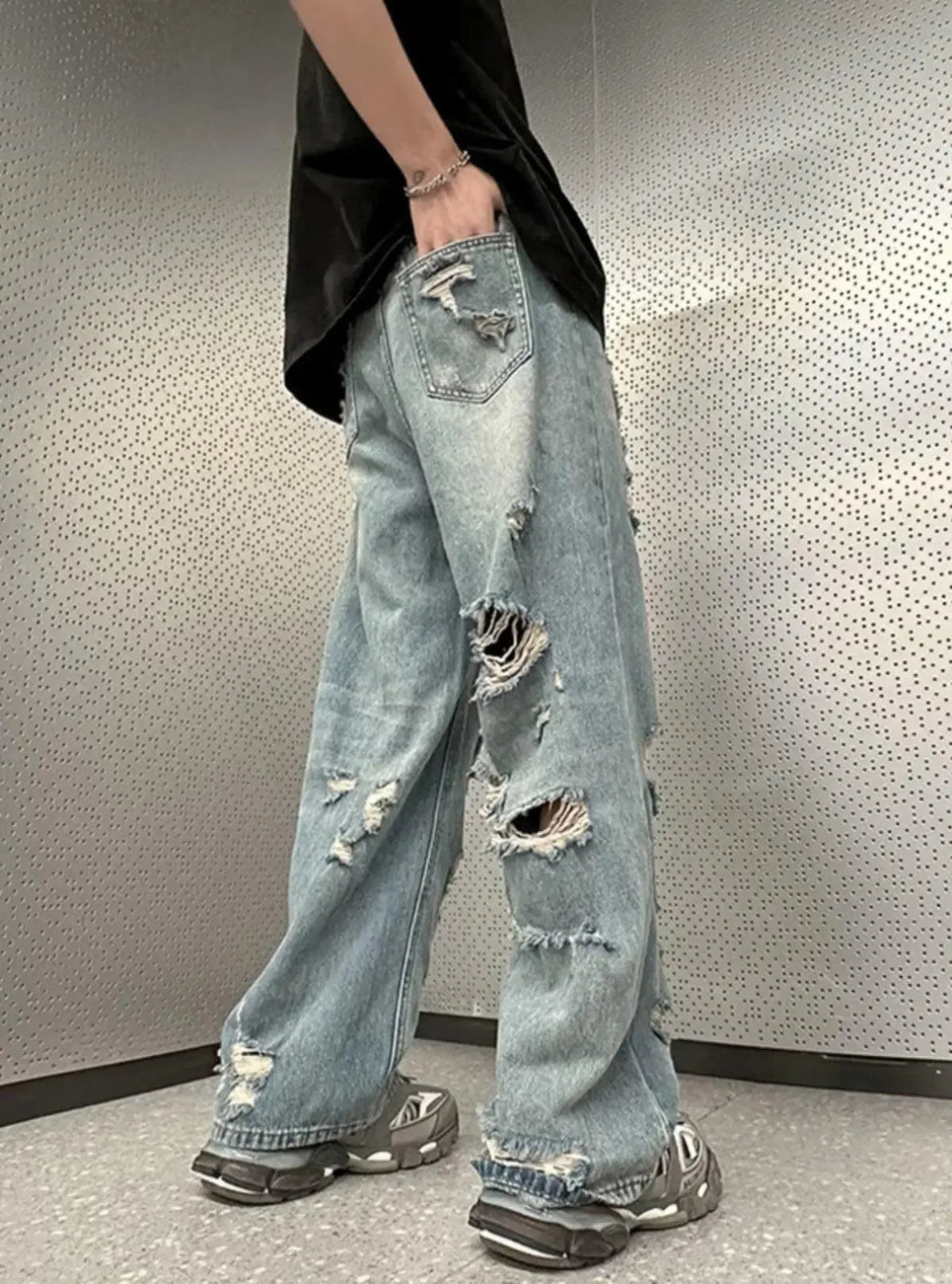 Person wearing light blue ripped jeans against a neutral background