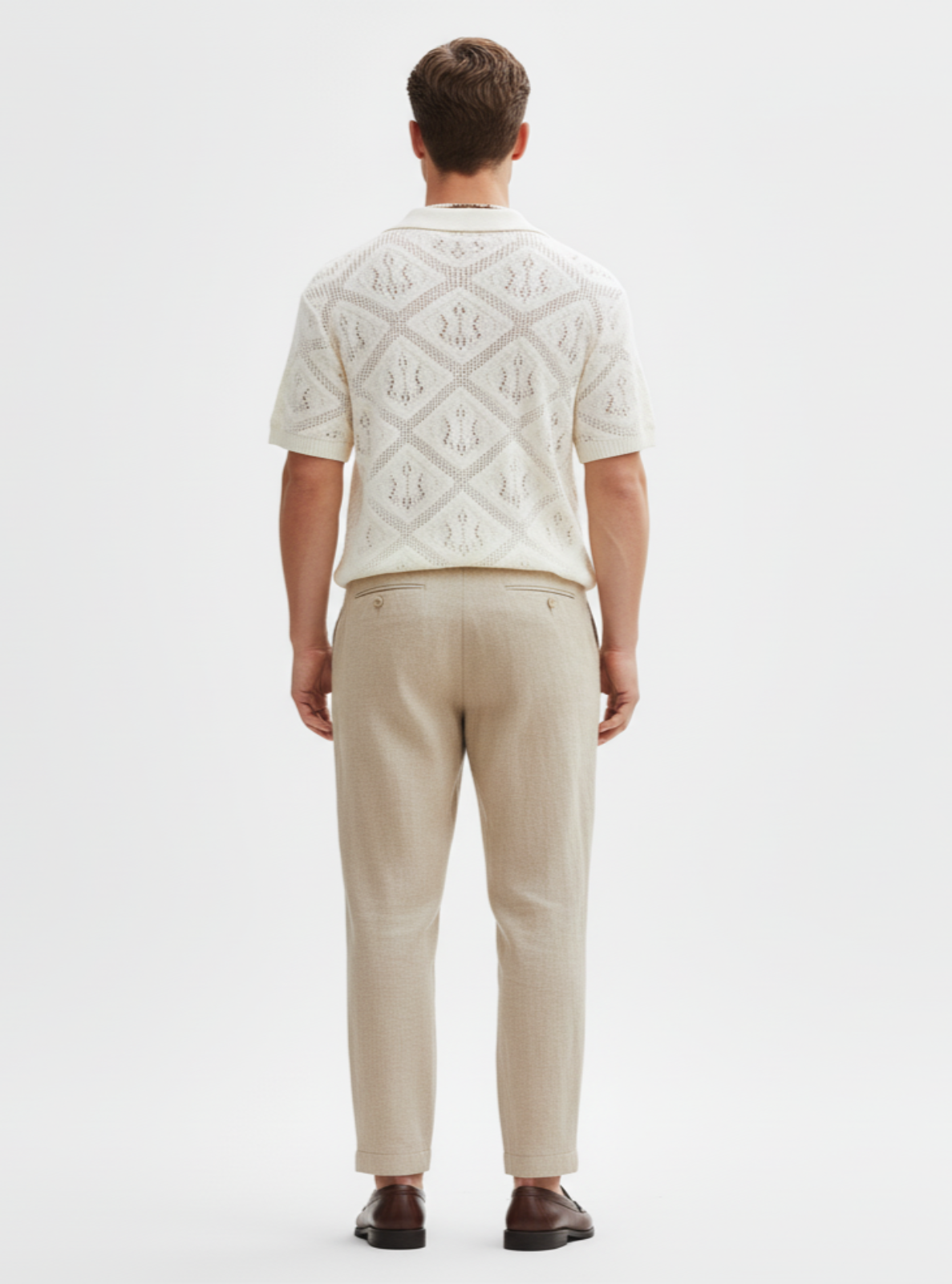 Man wearing a patterned white shirt and beige pants on a white background