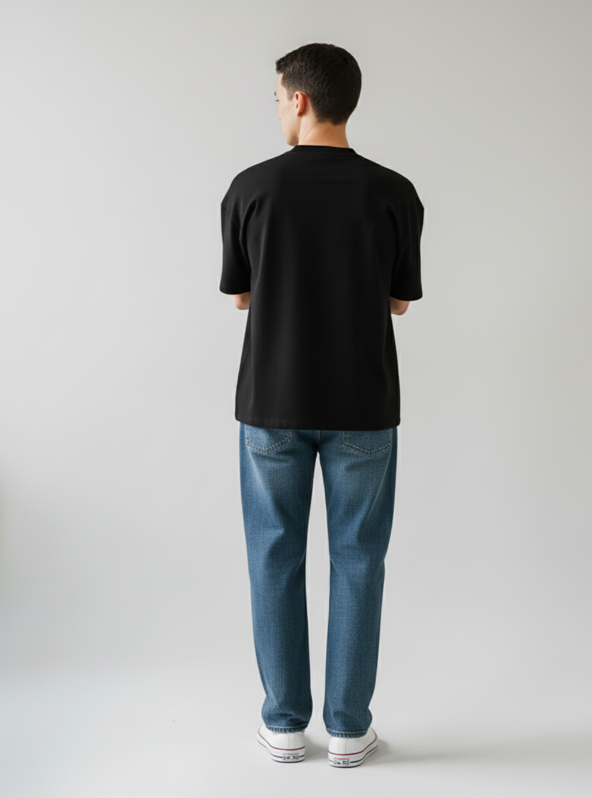 Person wearing a black t-shirt and blue jeans on a plain background