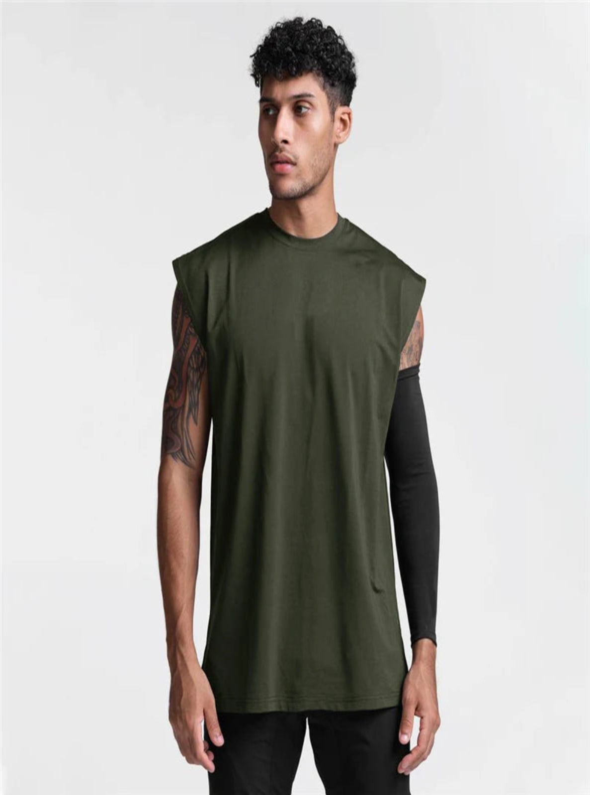 Man wearing a sleeveless green top with black sleeves on a white background